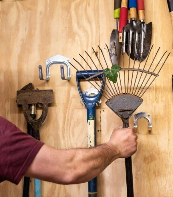 Garage organization with wall-mounted hooks holding rakes and gardening tools in a St. Louis home