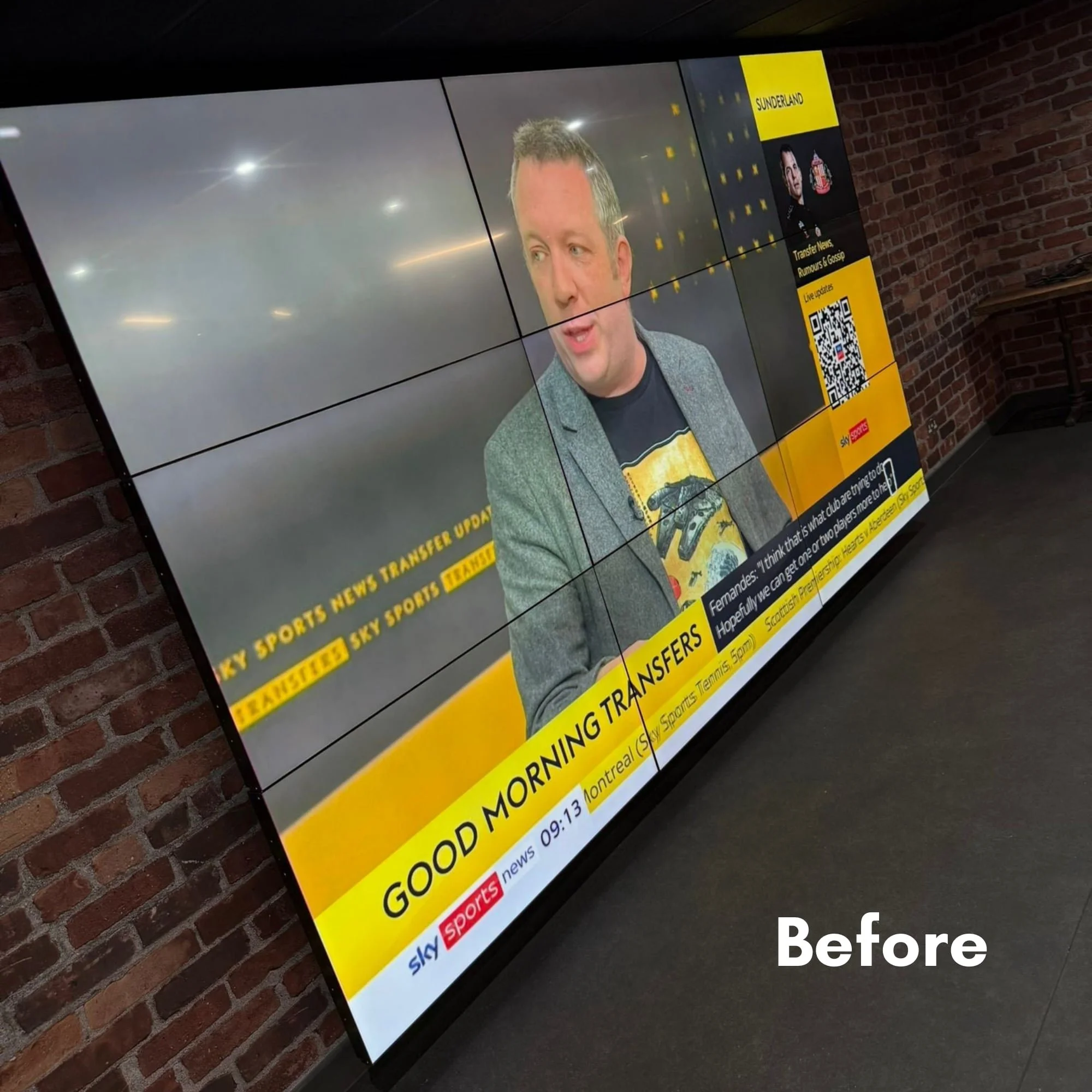 A large screen displaying a news broadcast from Sky Sports with a man speaking, on a brick wall background.