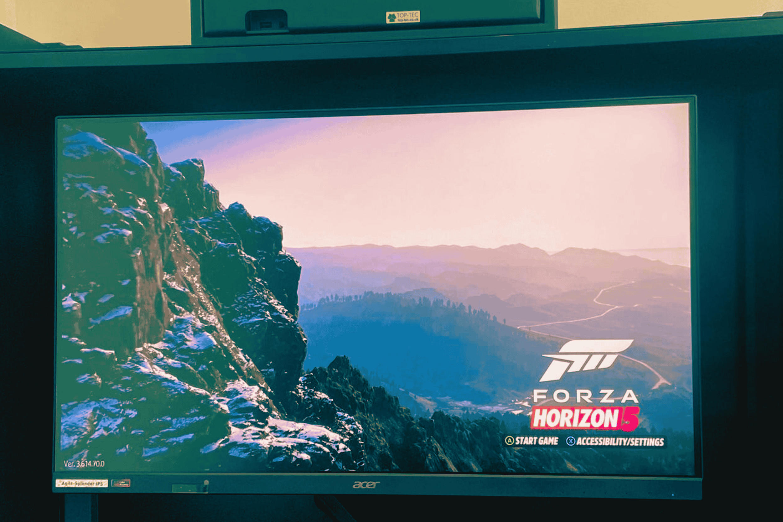 Video game screen showing the title for Forza Horizon 5 with a background of mountain scenery, rock formations, and a sunset sky.