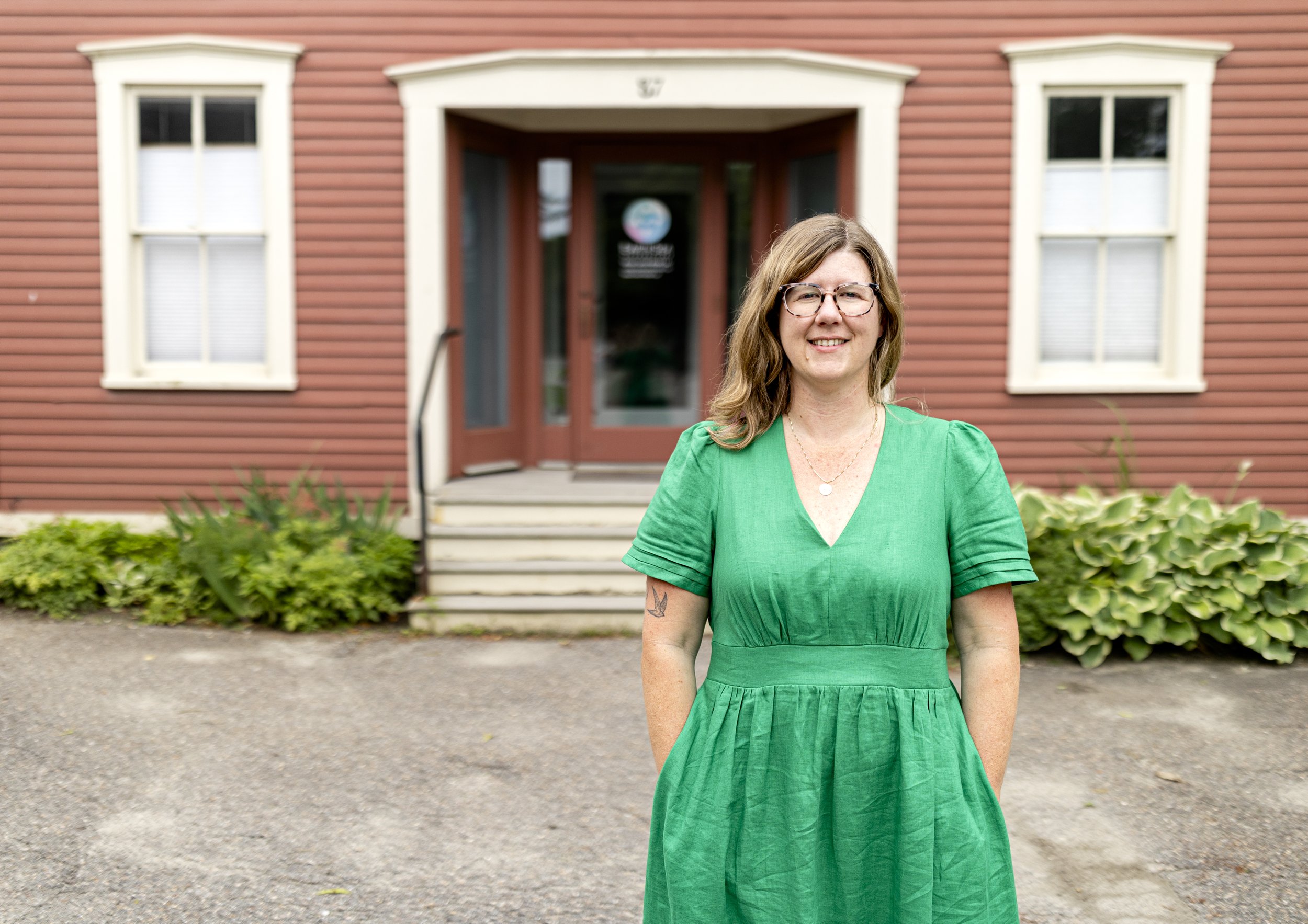 Women in green dress, standing in front of a red building.