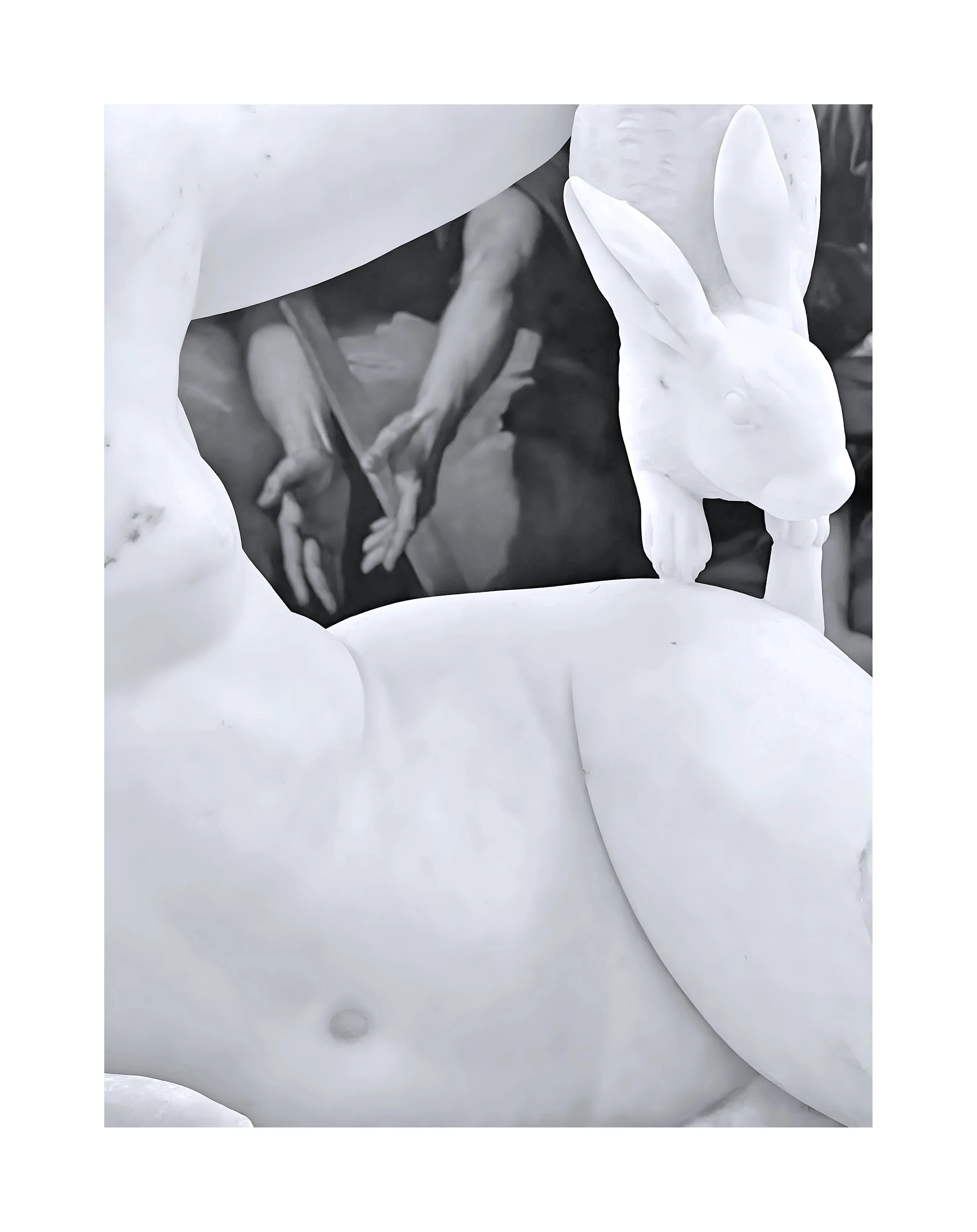 Statue blanche d'un lapin avec un œuf, partiellement visible, avec une photographie en noir et blanc en arrière-plan d'une personne.