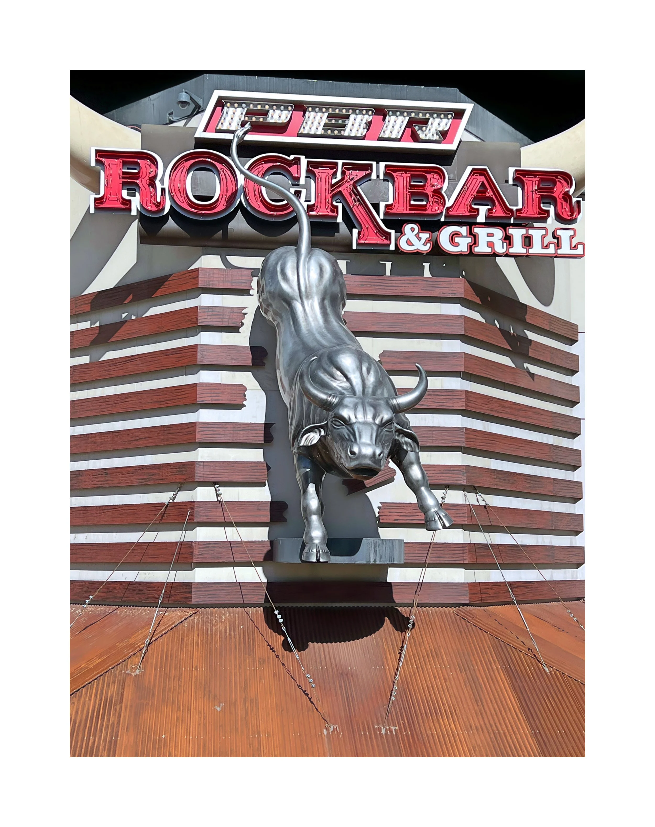 Signalisation extérieure du Rockbar & Grill avec un taureau en métal et un panneau lumineux marqué 'Rockbar & Grill'.