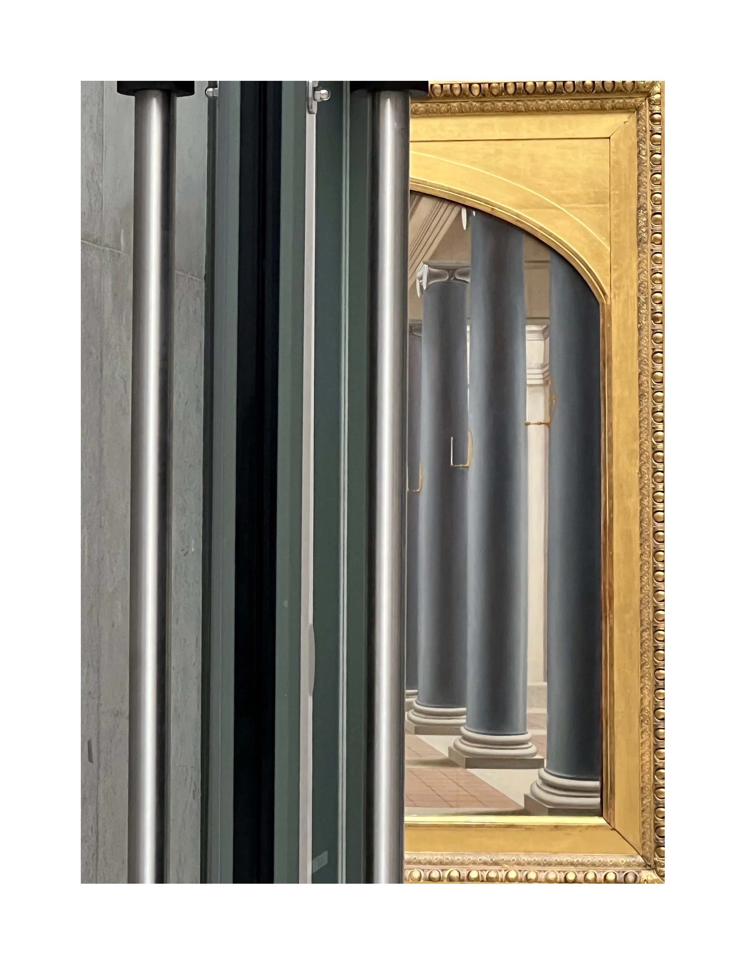 Un reflet dans un miroir montrant des colonnes noires et un cadre doré dans un bâtiment historique