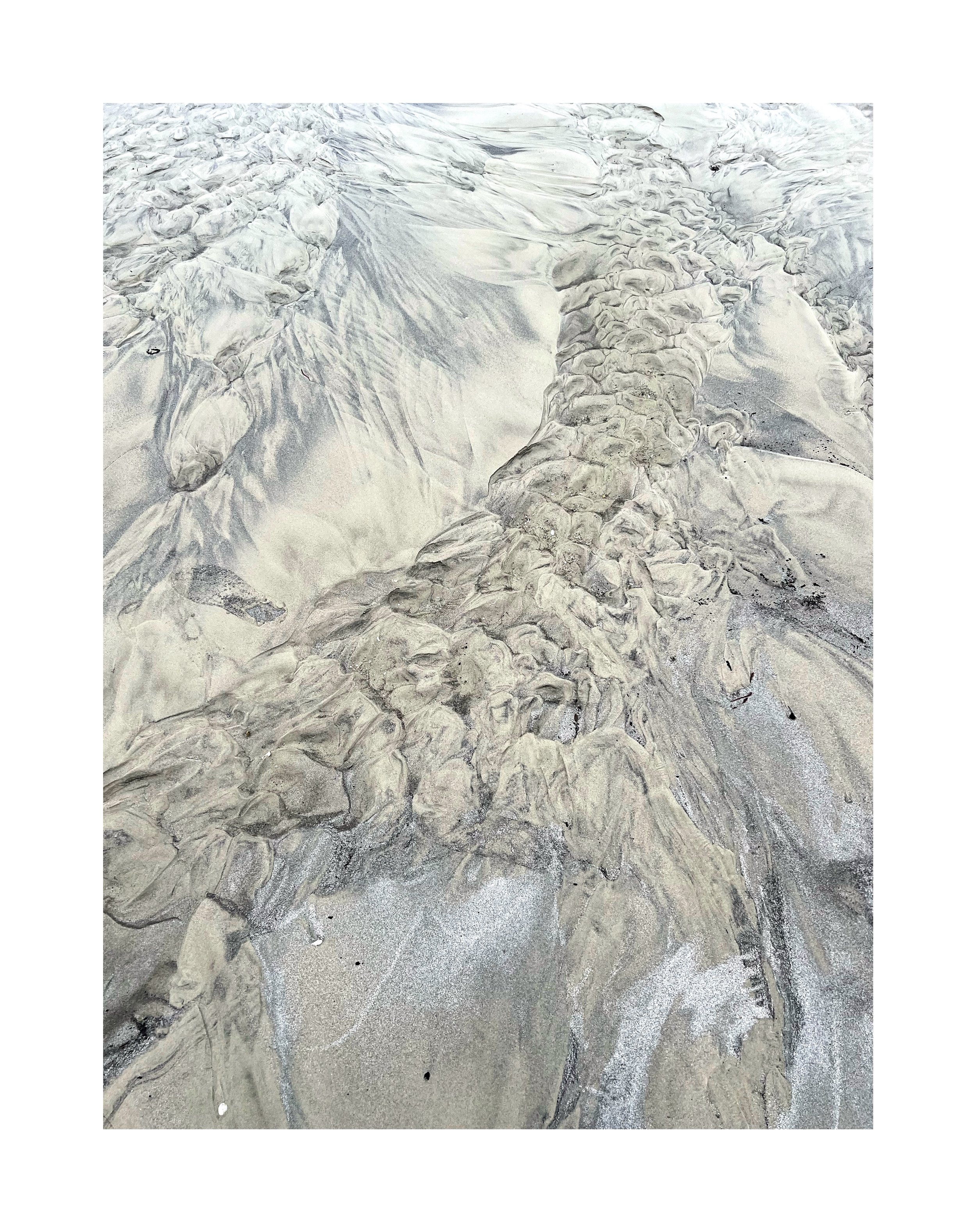 Sable avec des formations rocheuses et de l'eau en mouvement.