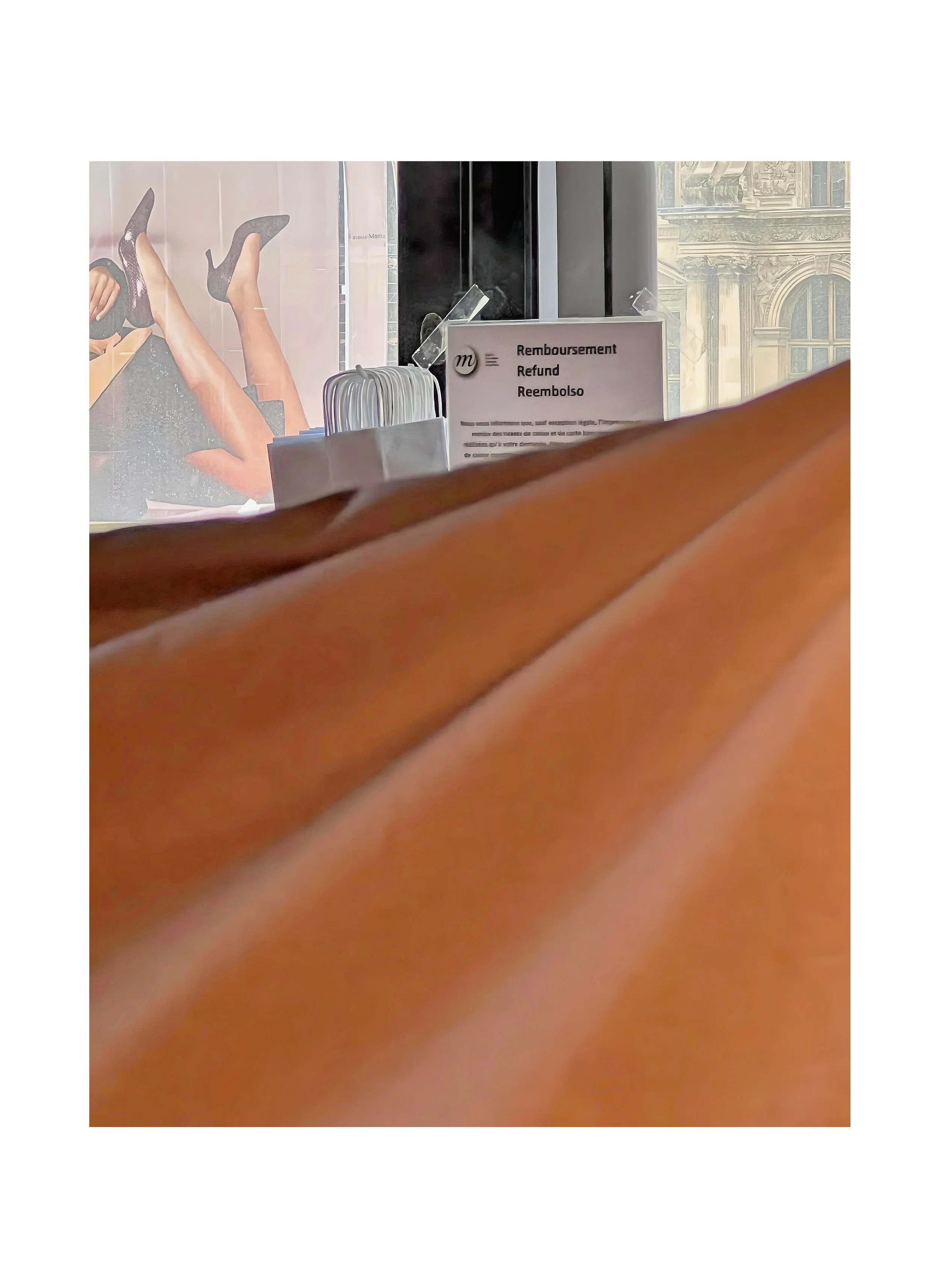 vue partielle d'un comptoir avec un panneau indiquant le remboursement en plusieurs langues, des paquets de mouchoirs, un fond avec une affiche et une fenêtre. 