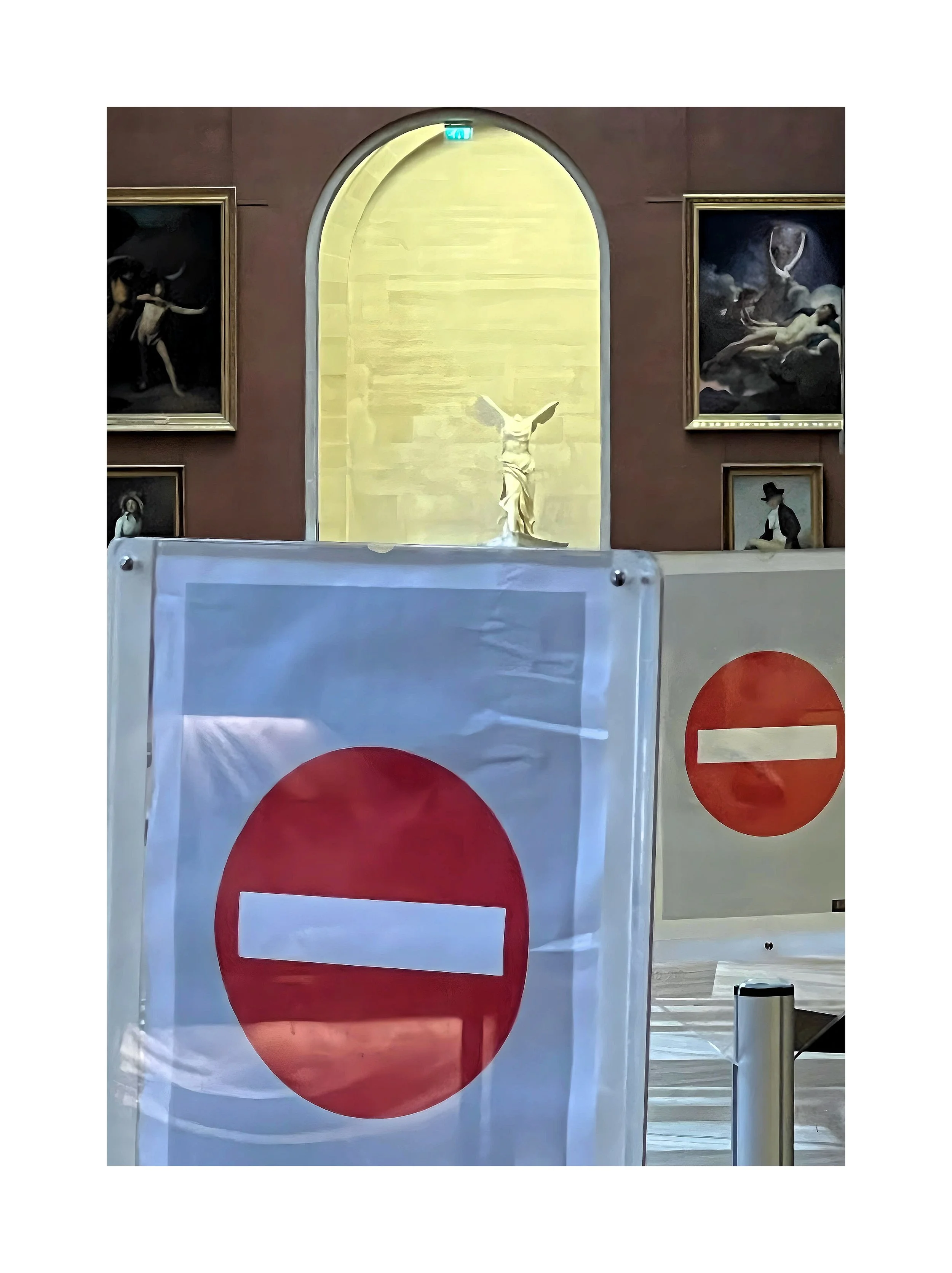 Une salle d'exposition avec une sculpture au centre, encadrée par des peintures, et des panneaux de signalisation 'sens interdit' en premier plan.