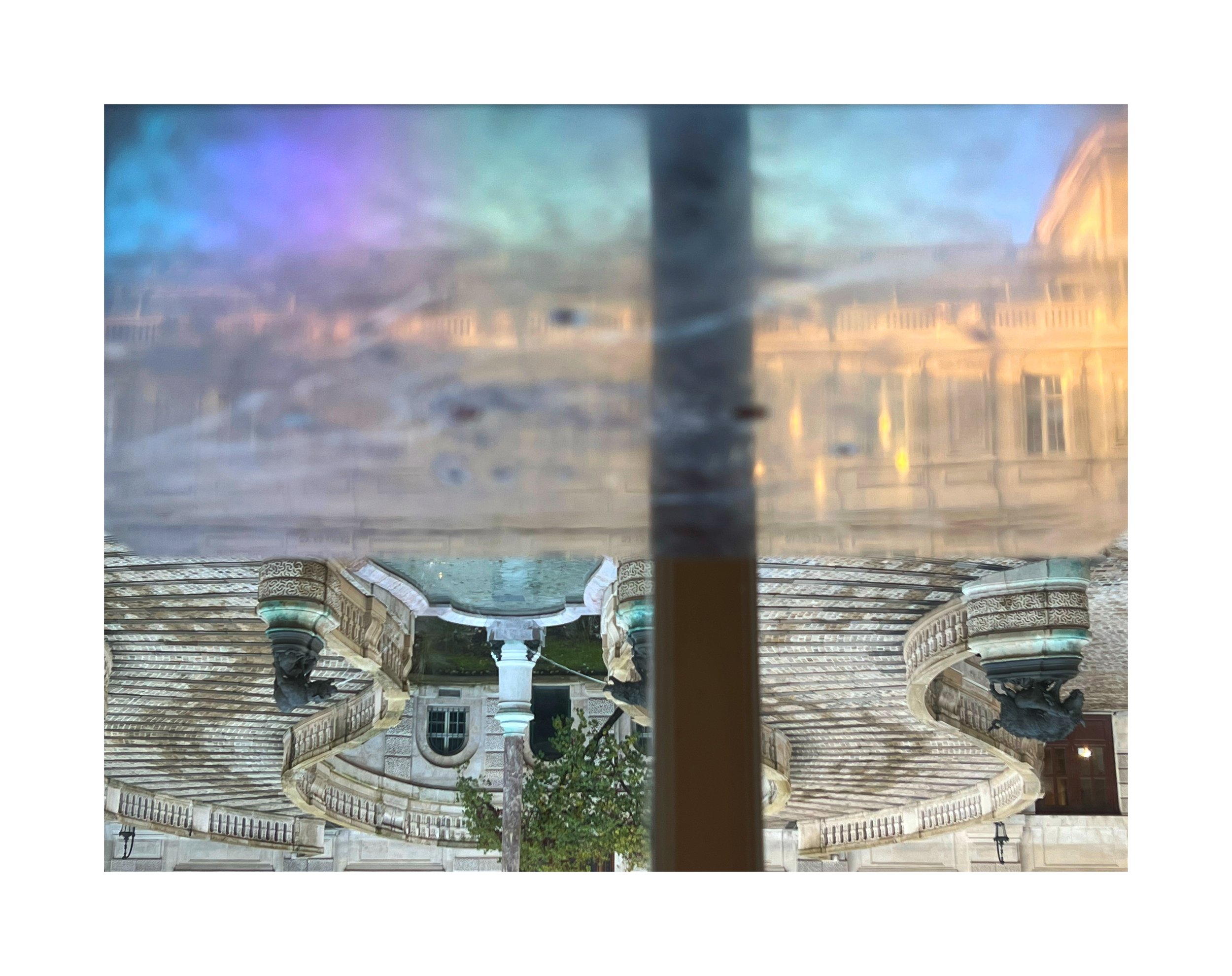 Une photo d'une place publique en pierre avec des sculptures de lions en bronze, entourée de bâtiments historiques en pierre, vue à travers une vitre floue ou un matériau translucide.