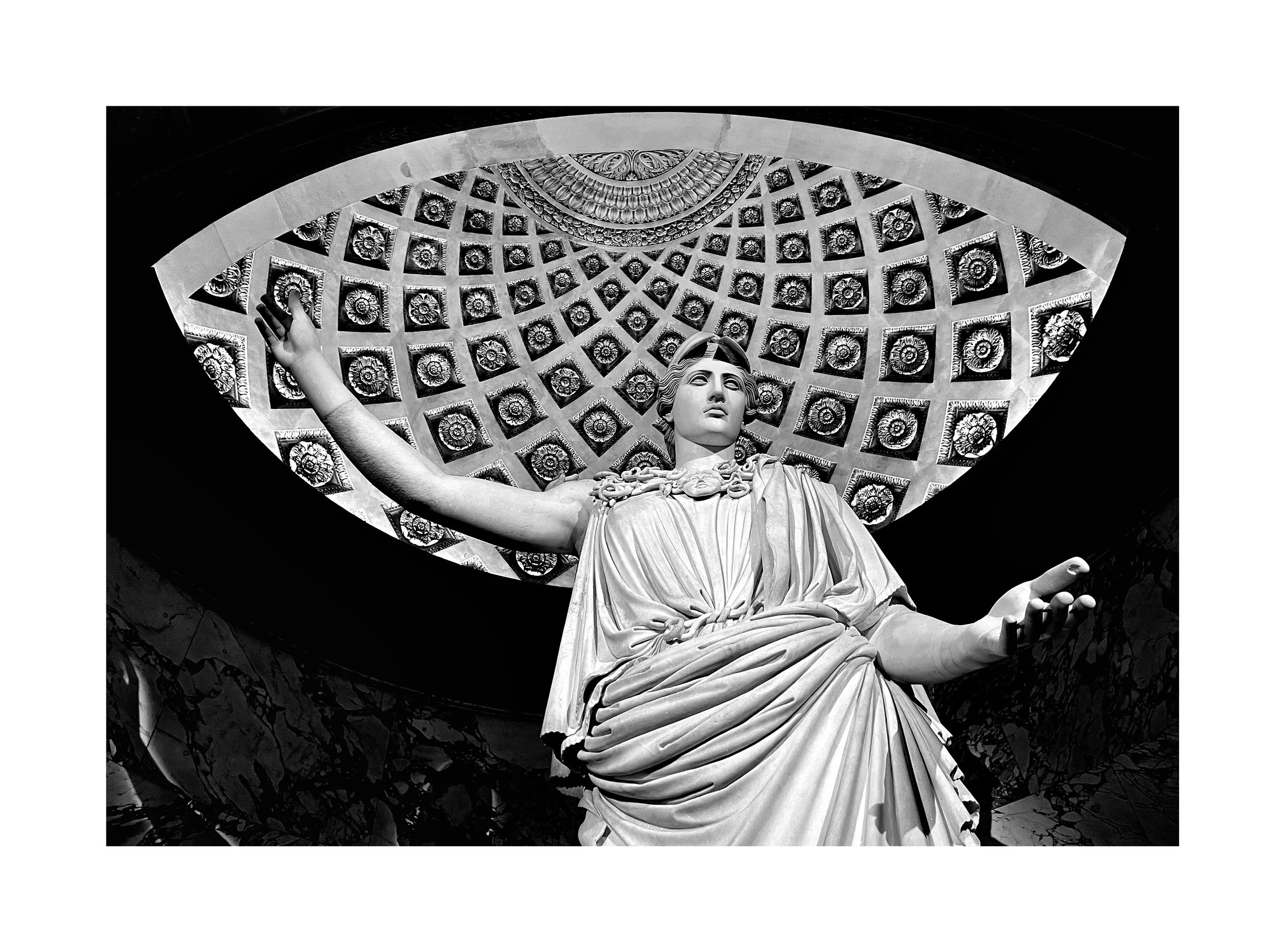 Statue en marbre d'une femme avec un drapé, assise avec les bras étendus, sous un plafond orné de motifs géométriques.