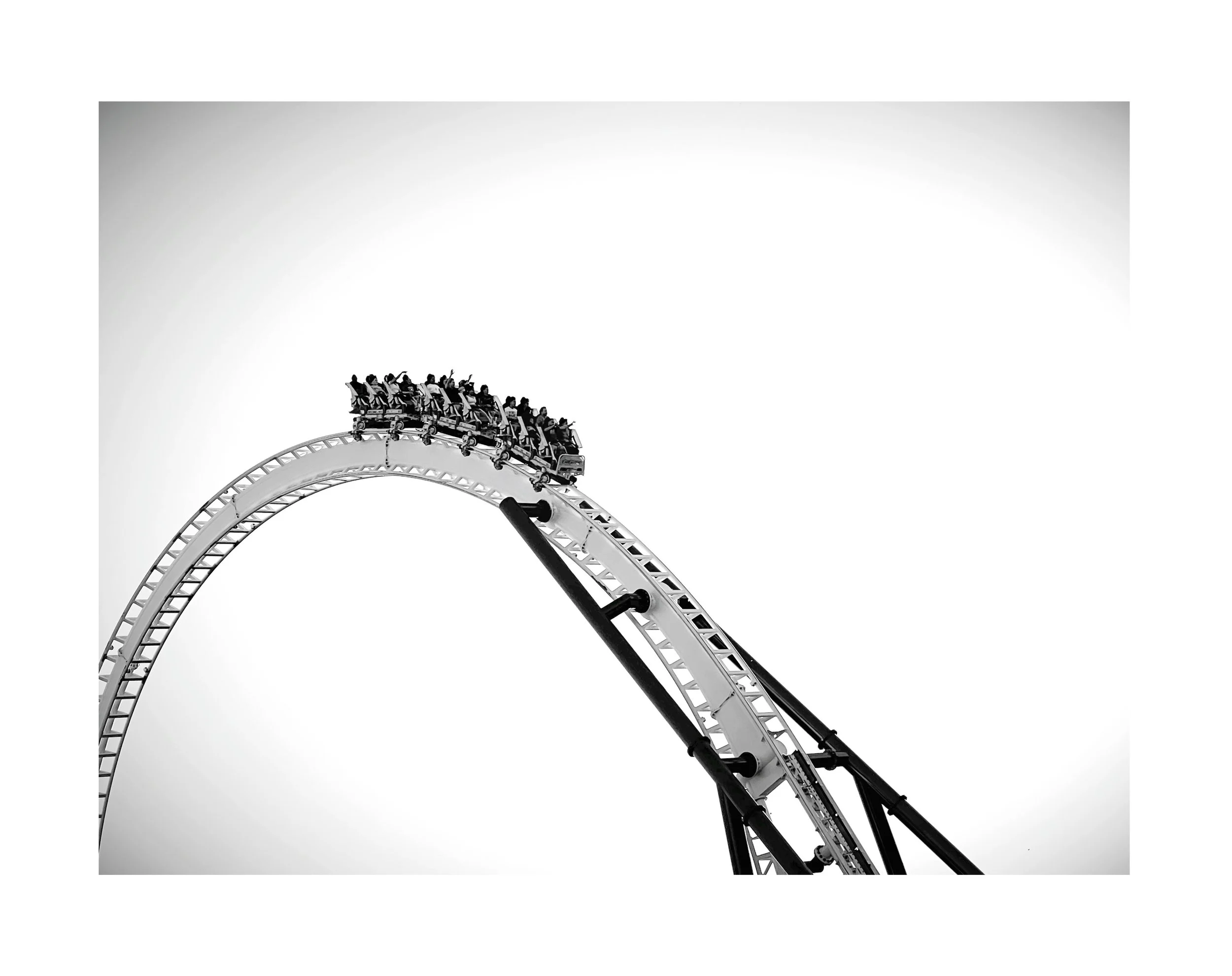 Une montagne russe noire et blanche avec un groupe de personnes en haut du virage.