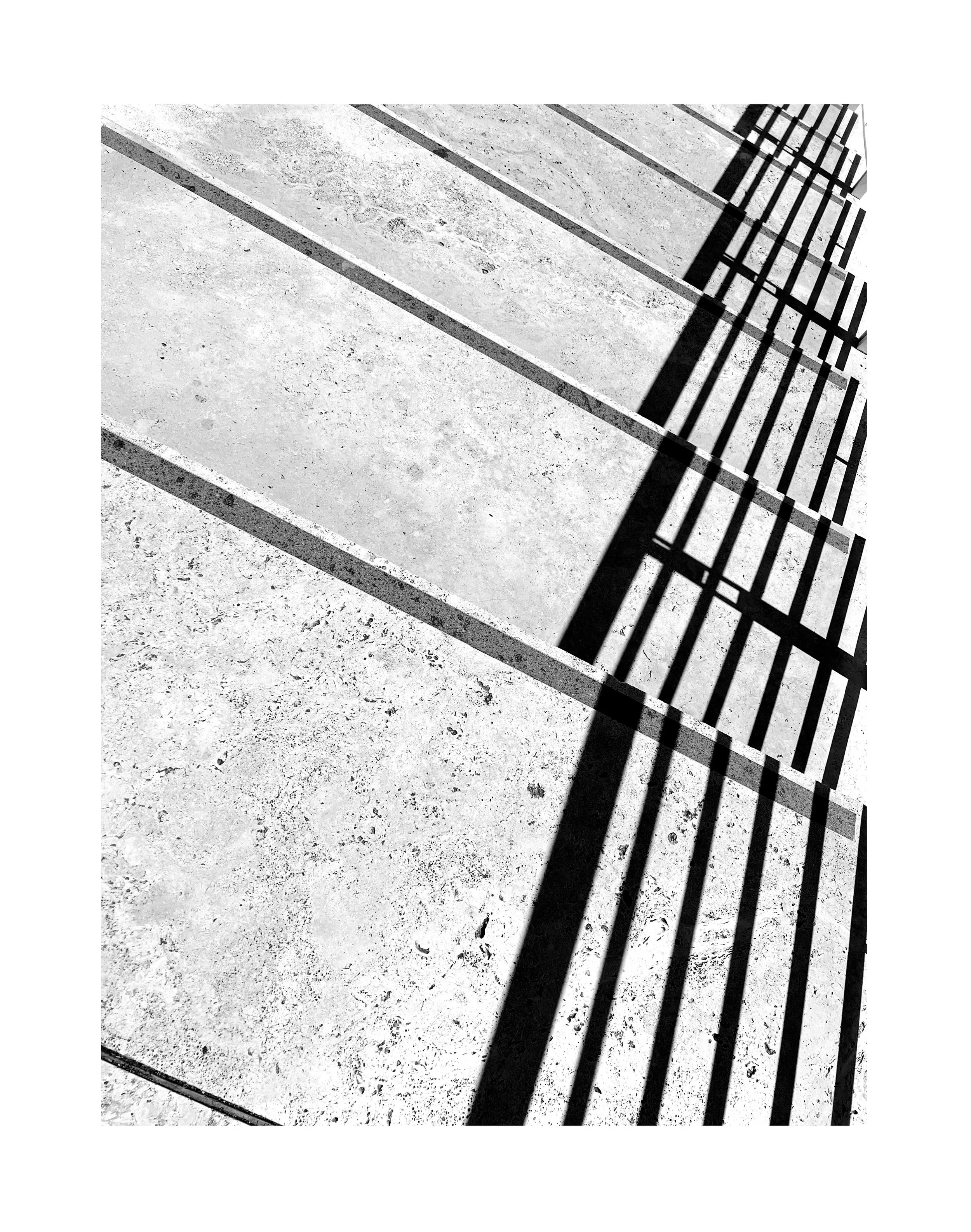 Ombre de barrière en métal sur un sol en béton éclairé par le soleil.