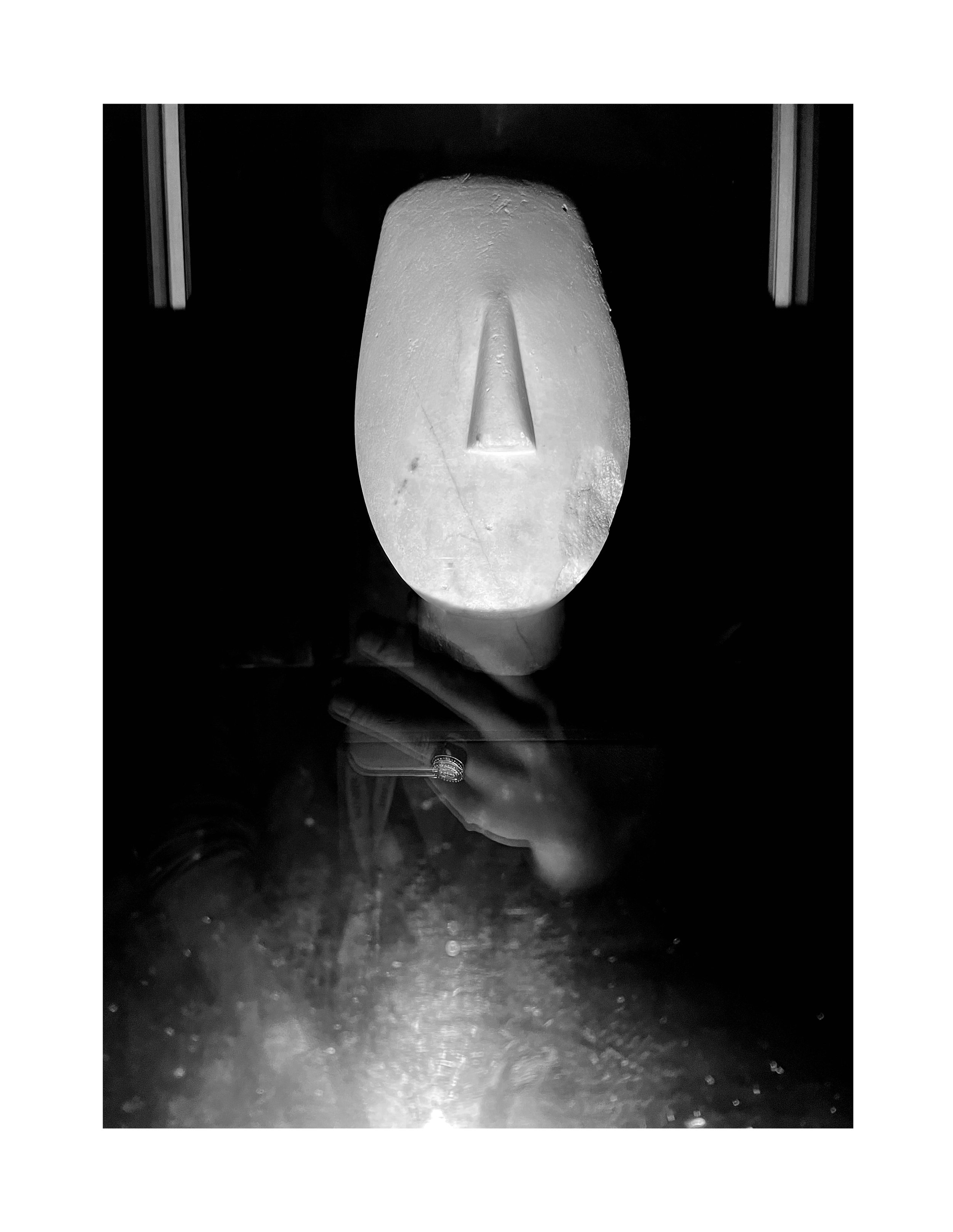 Une sculpture en forme de visage avec un nez long et une surface lisse, vue de face, monochrome.