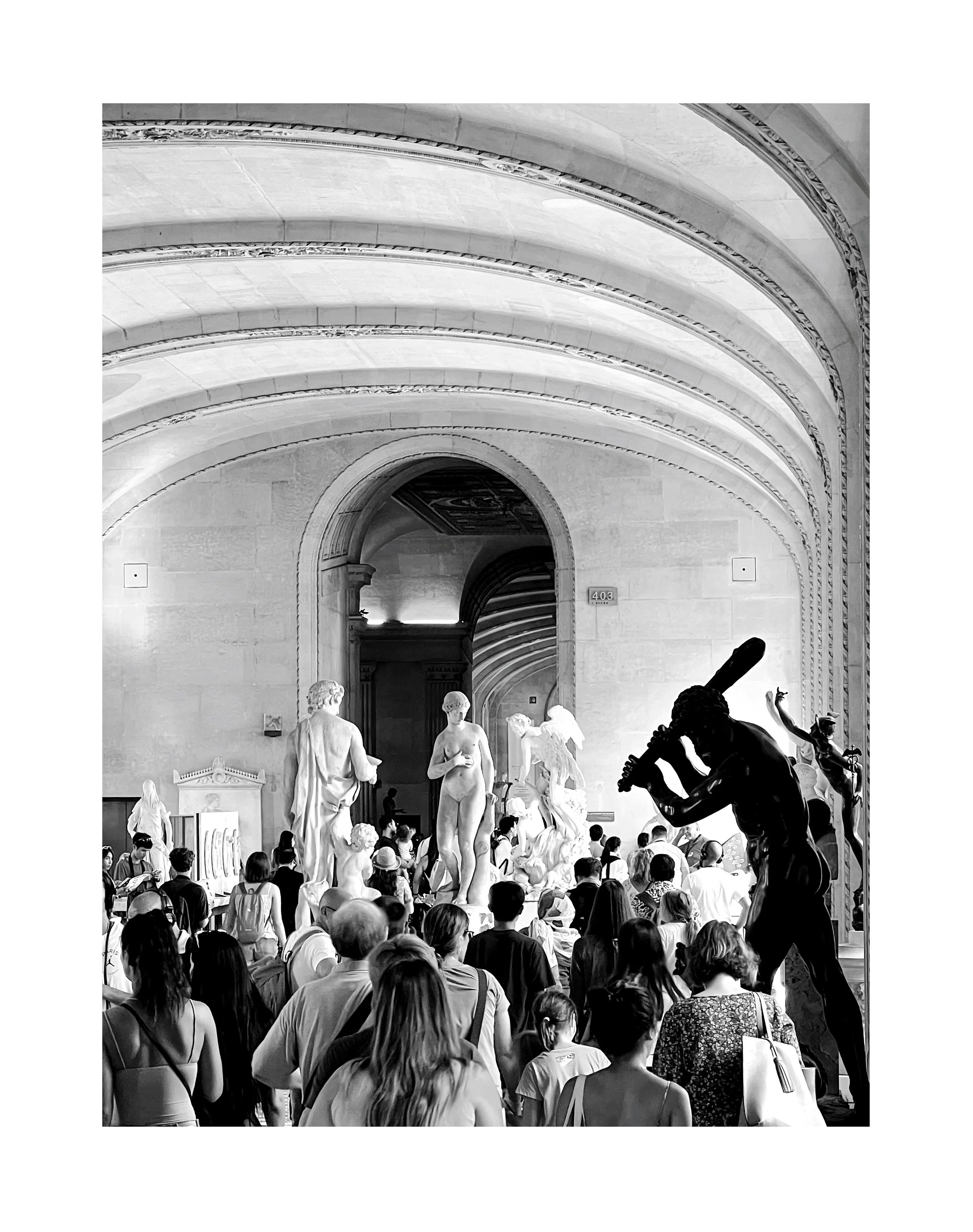 Salle d'exposition ou musée avec sculptures classiques et sculptures modernes, foule de visiteurs, architecture remarquable avec arches et plafond décoré.