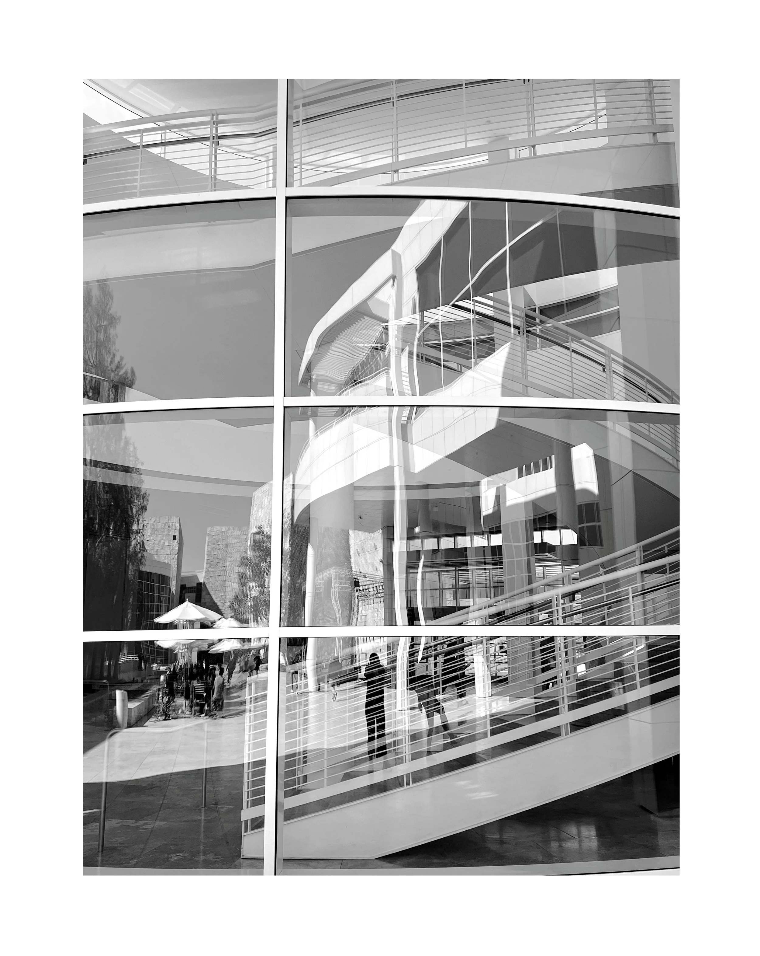 Reflet d'un bâtiment moderne avec des escaliers intérieurs visibles à travers une grande façade en verre.