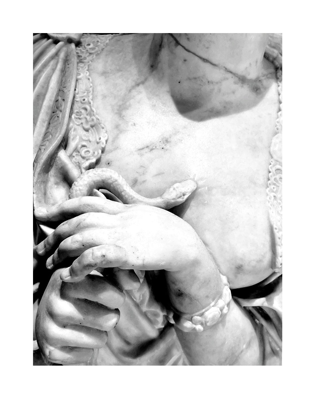 Détail d'une sculpture en marbre représentant une partie du corps humain avec des mains, un bracelet et de la nervosité dans la sculpture.