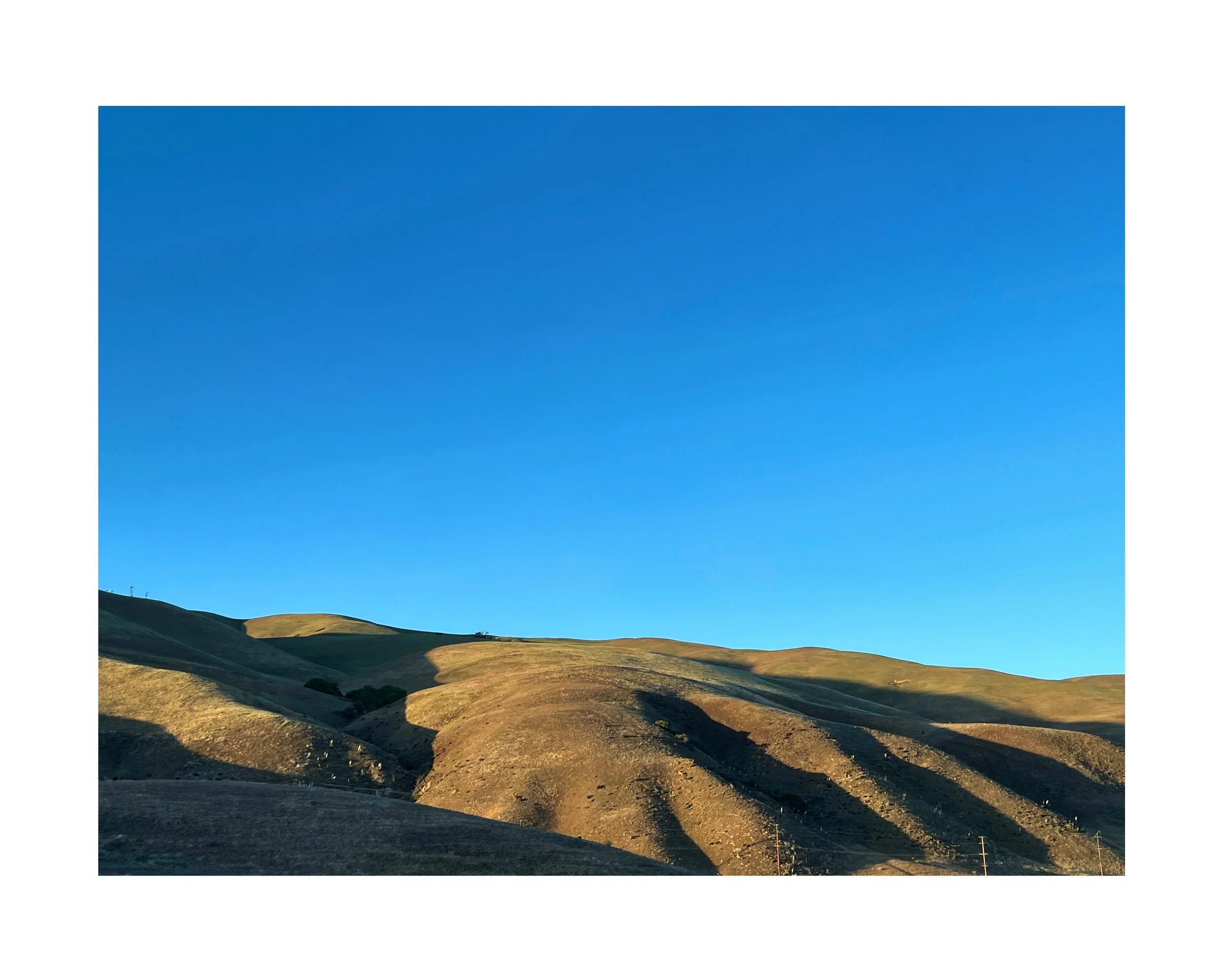 Collines en terre sèche sous un ciel bleu sans nuages.