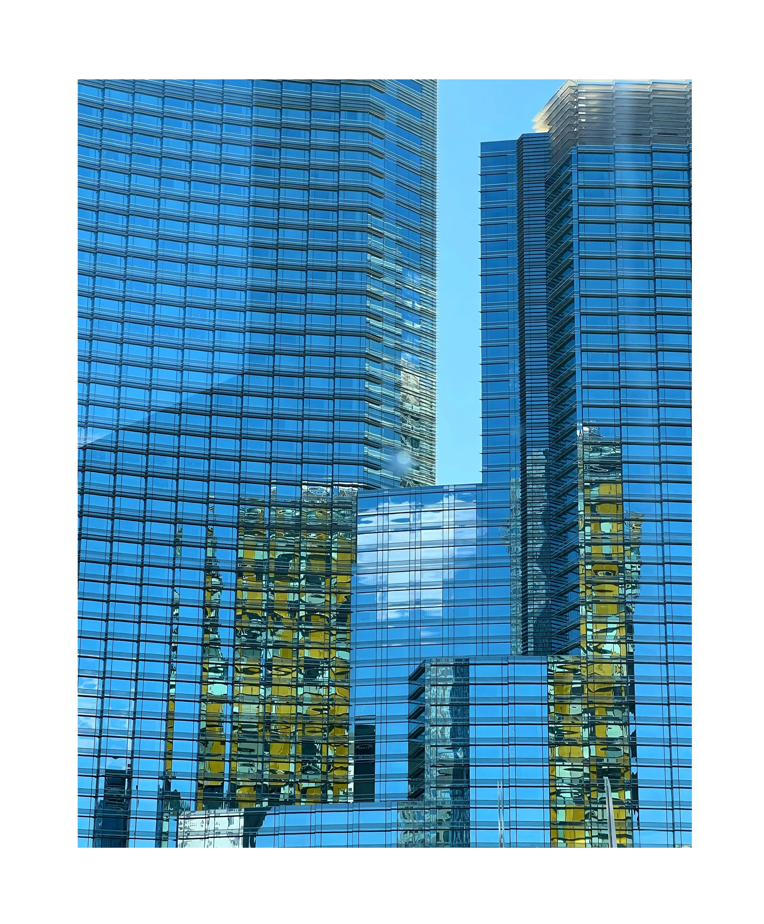 Gratte-ciel en verre reflétant le ciel et d'autres bâtiments.