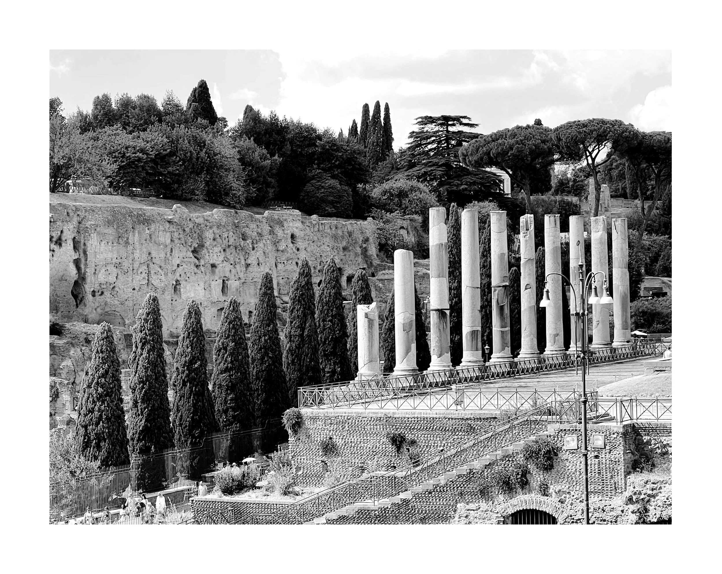 Ruines antiques avec colonnes en pierre et arbres dans un parc."}