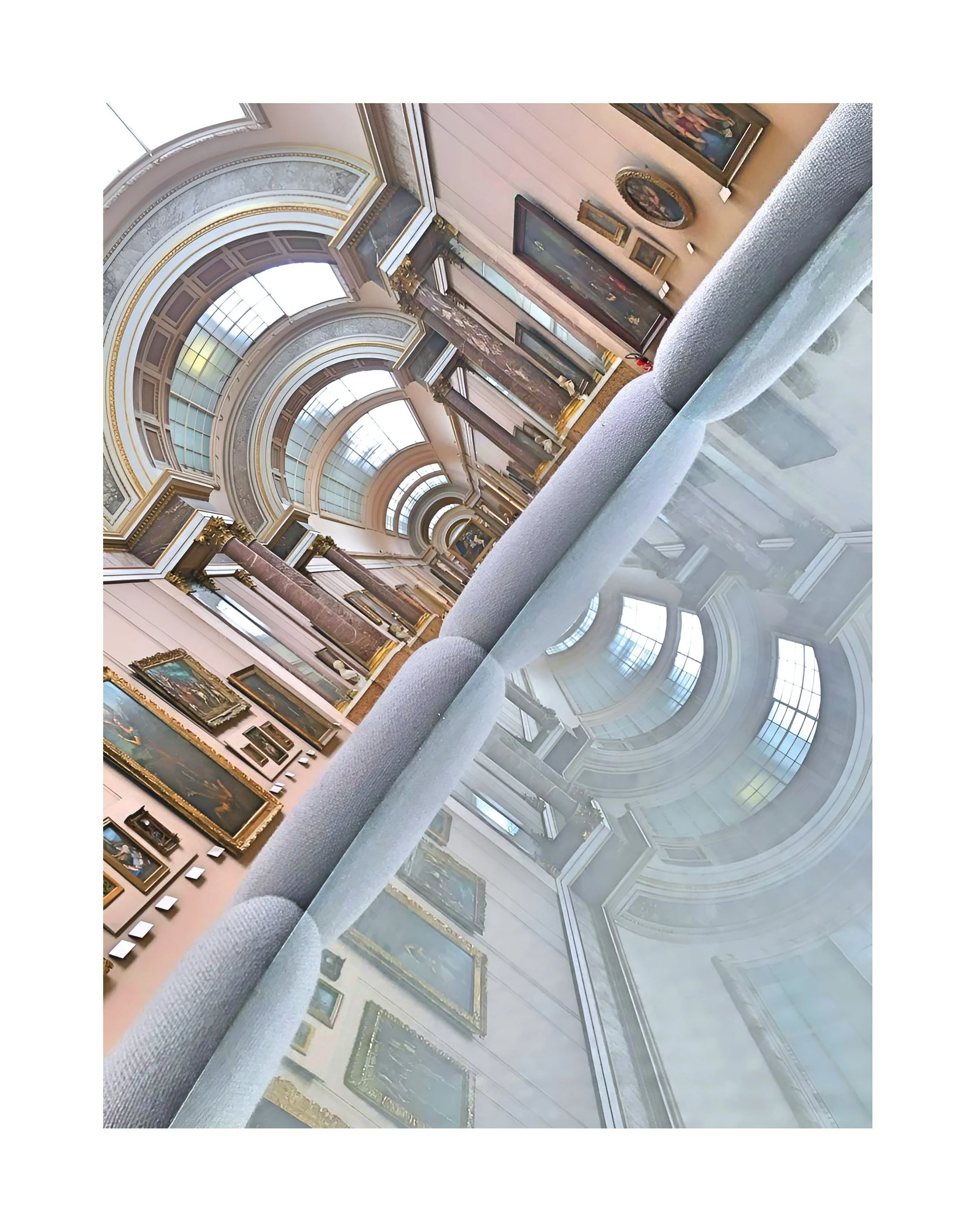 Une salle d'exposition d'un musée d'art avec des tableaux suspendus aux murs et un grand plafond arrondi avec des fenêtres de style ancien.