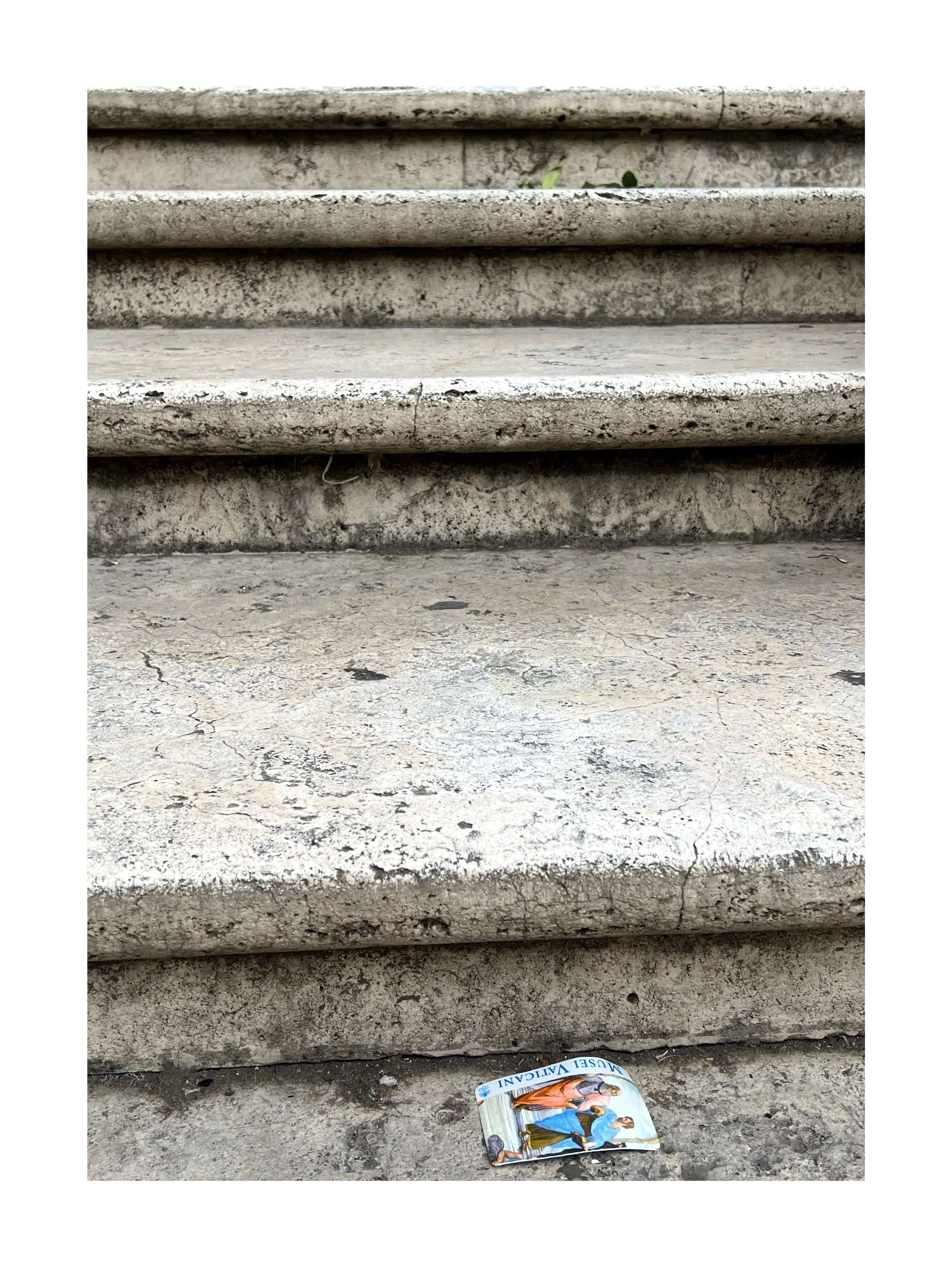 Escalier en pierre usée avec un déchet de papier à terre sous les marches.