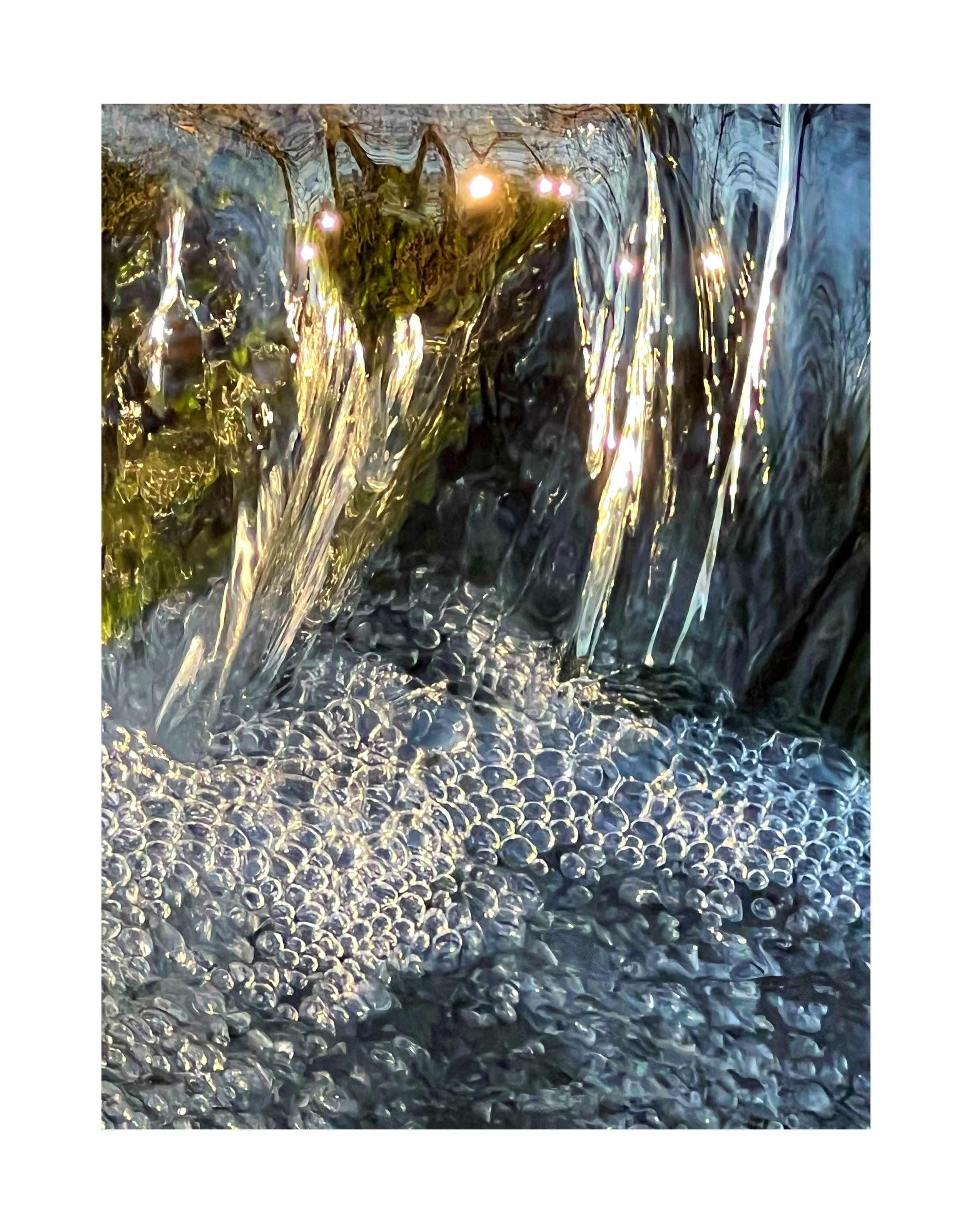 Photo d'une cascade d'eau avec des bulles et des éclats de lumière.