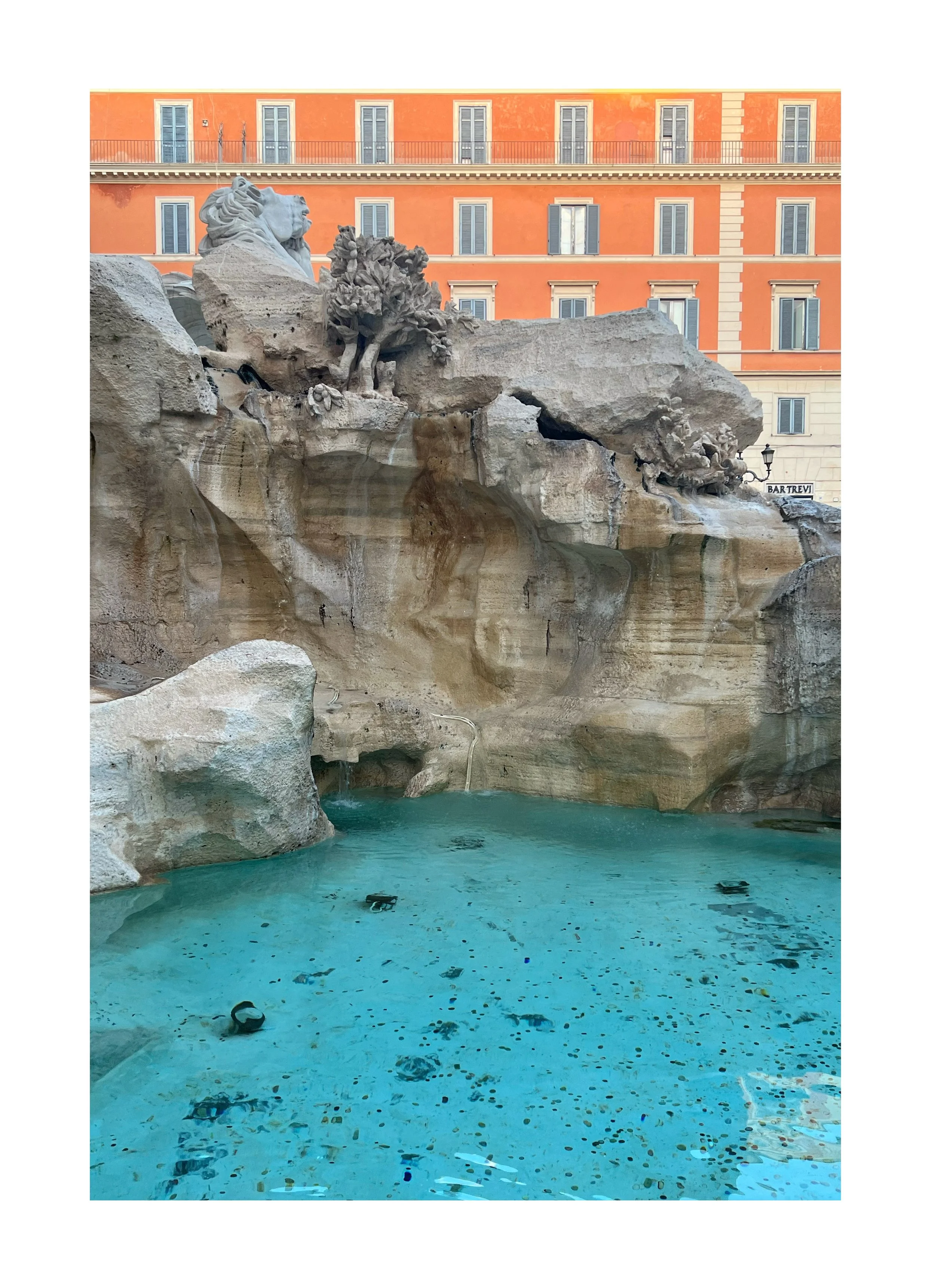 Fontaine baroque avec sculptures de lions et d'arbres en pierre, eau turquoise dans le bassin et bâtiment orange en arrière-plan à Rome.