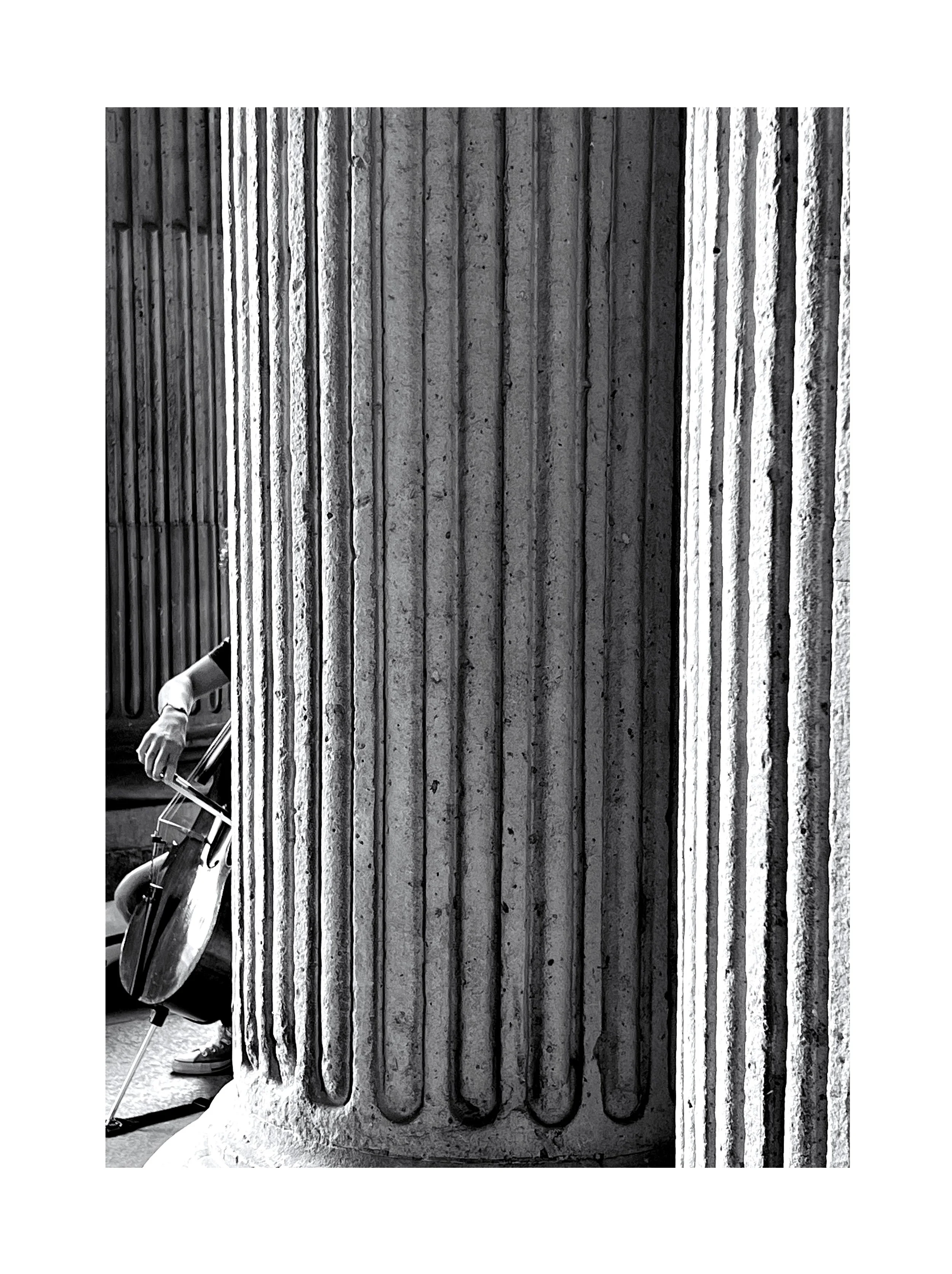 Une colonne en béton avec des rainures verticales, partiellement obstruée par la silhouette d'un homme jouant au golf, dont la main et le club de golf sont visibles à gauche.