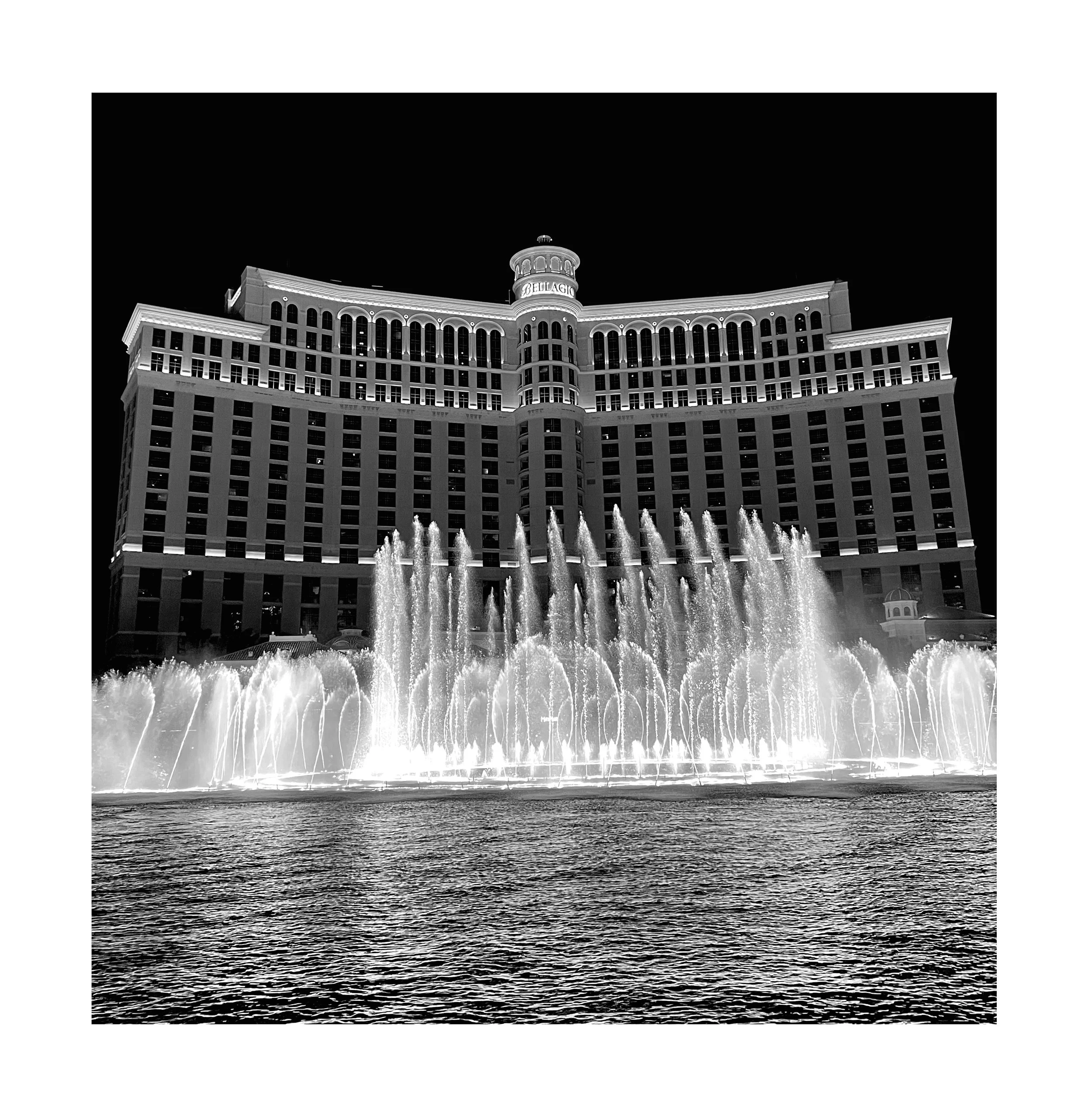 L'hôtel Bellagio avec sa fontaine illuminée au devant, en noir et blanc.