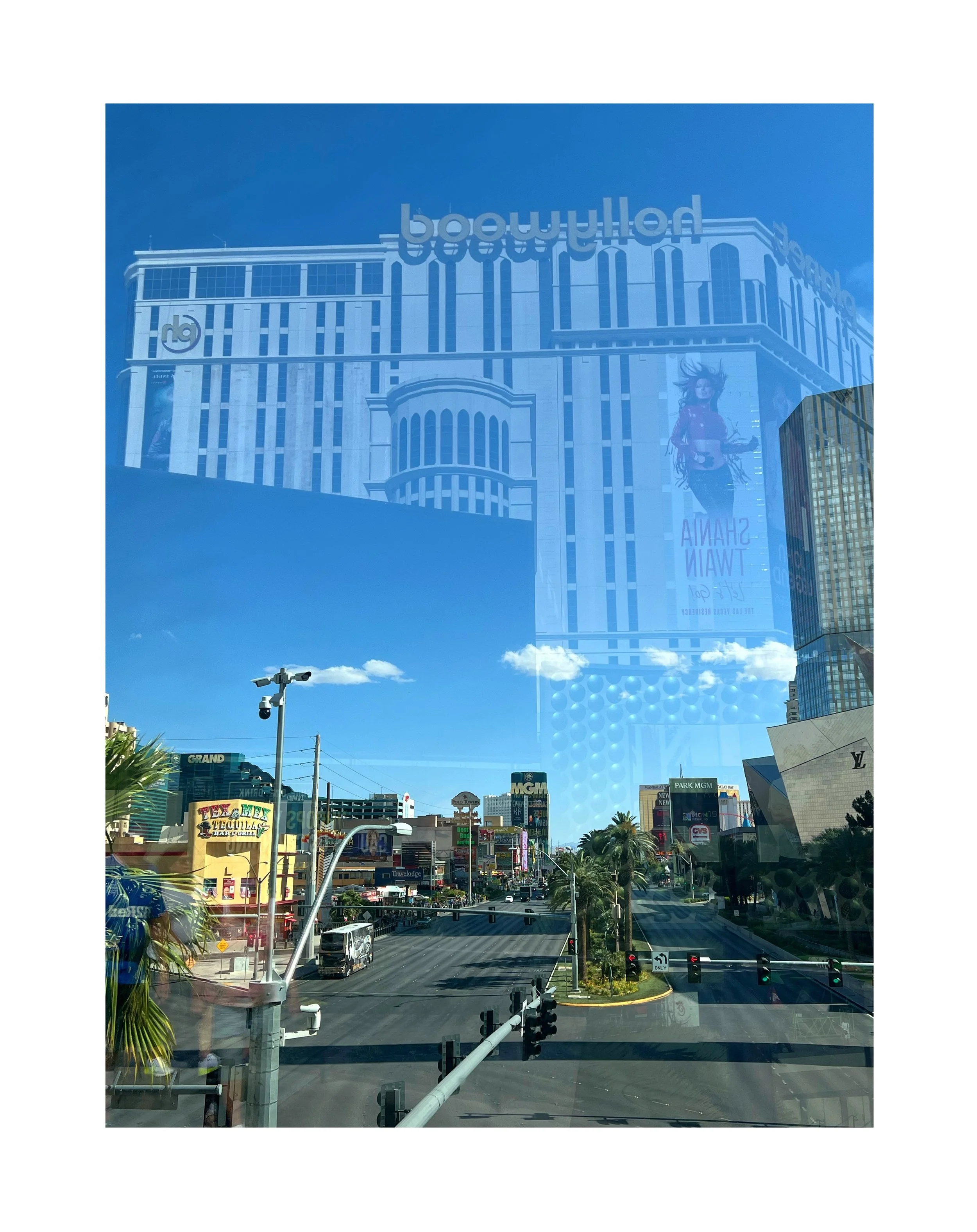 Reflet d'un bâtiment moderne avec publicité sur une vitre de voiture. La scène montre une rue animée avec des panneaux publicitaires et des bâtiments en plein jour.