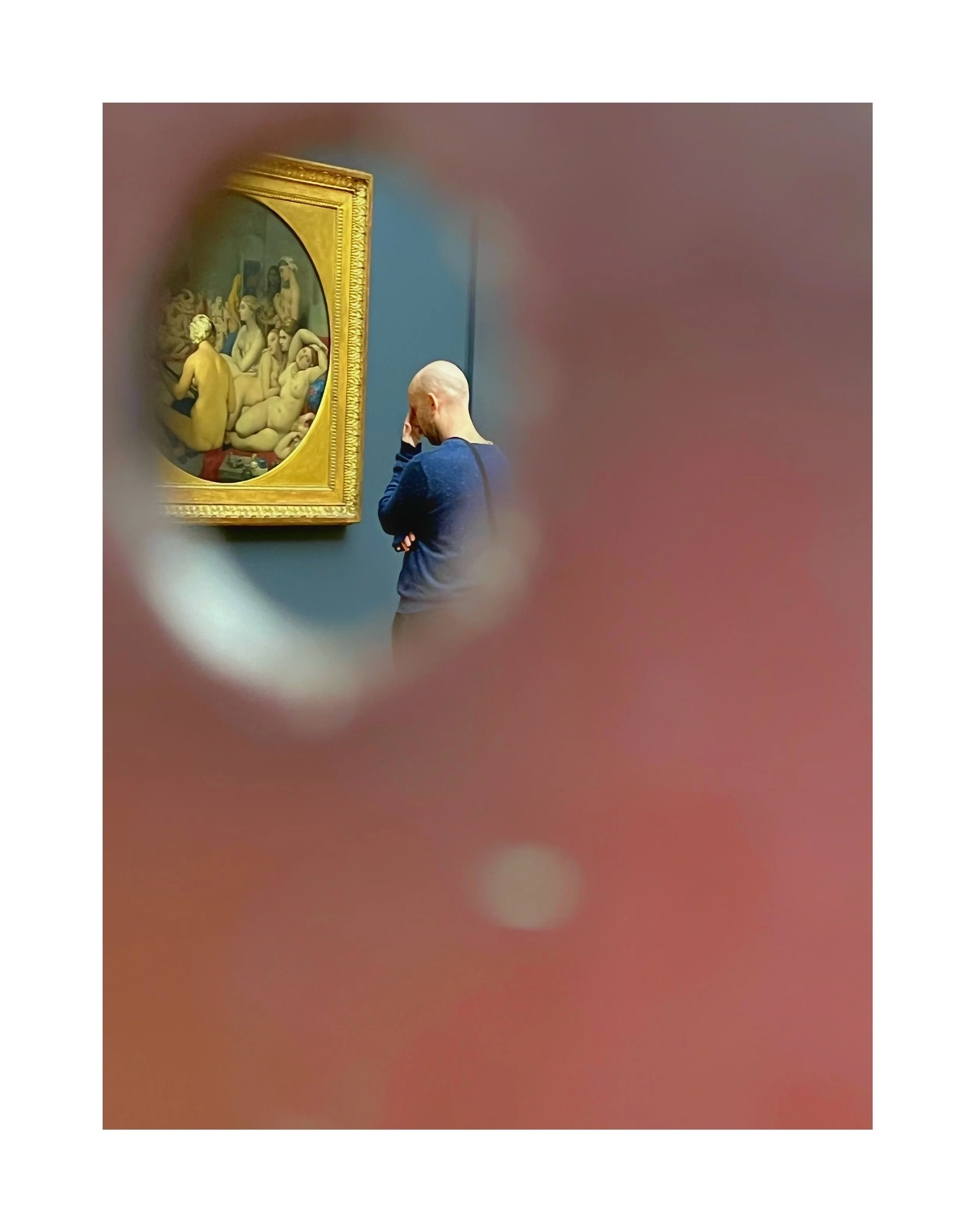 Une personne regardant une peinture dans un musée, vue à travers un entour du doigt ou de l'objectif de l'appareil photo.