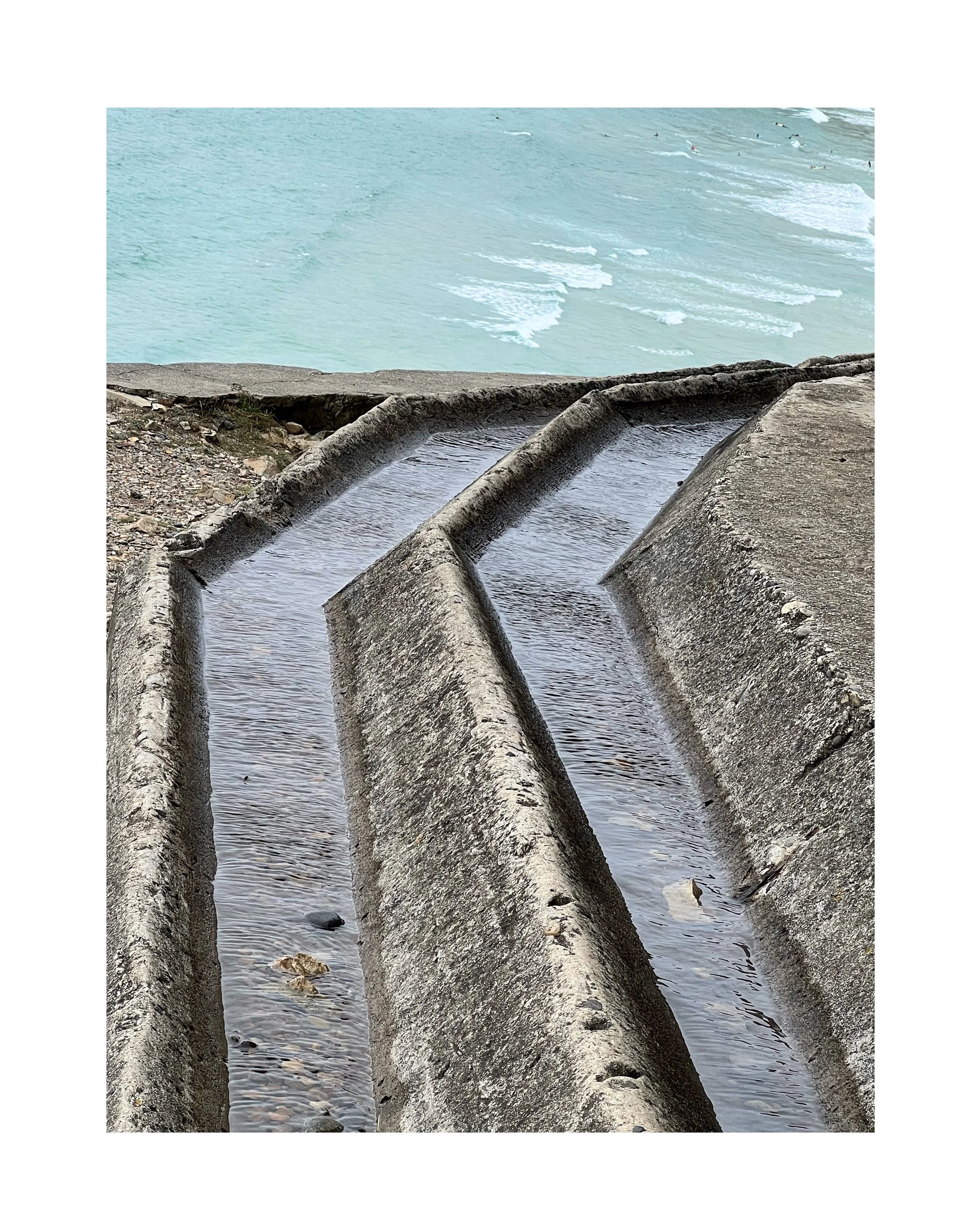 Nest de poissons en béton sur la plage, avec vue sur la mer en arrière-plan.