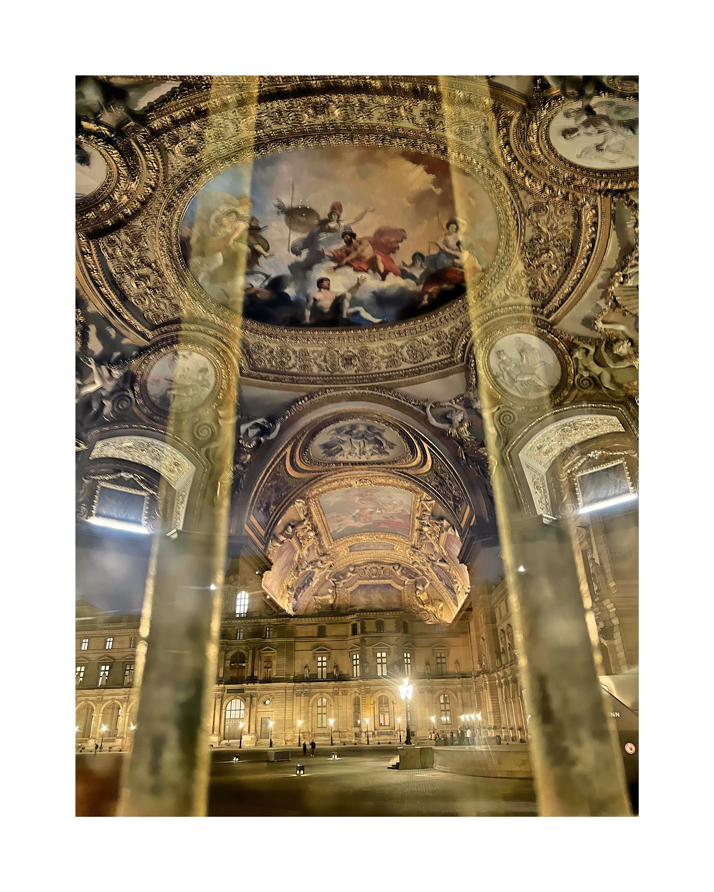 Vue de l'intérieur d'un bâtiment historique, probablement un palais ou un musée, avec un plafond richement décoré et peint, vu à travers des barreaux en métal. Le plafond est orné de fresques et de moulures dorées.