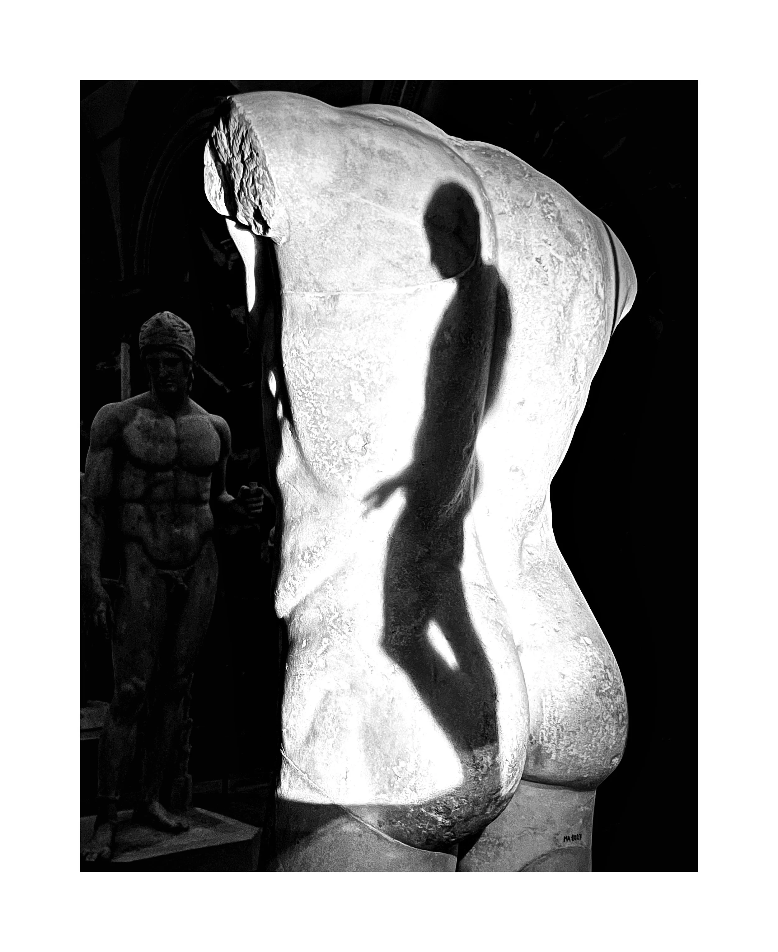 Une sculpture de corps humain en marbre avec une silhouette de personne projetée à l'intérieur, accompagnée d'une statue de figure masculine en arrière-plan.