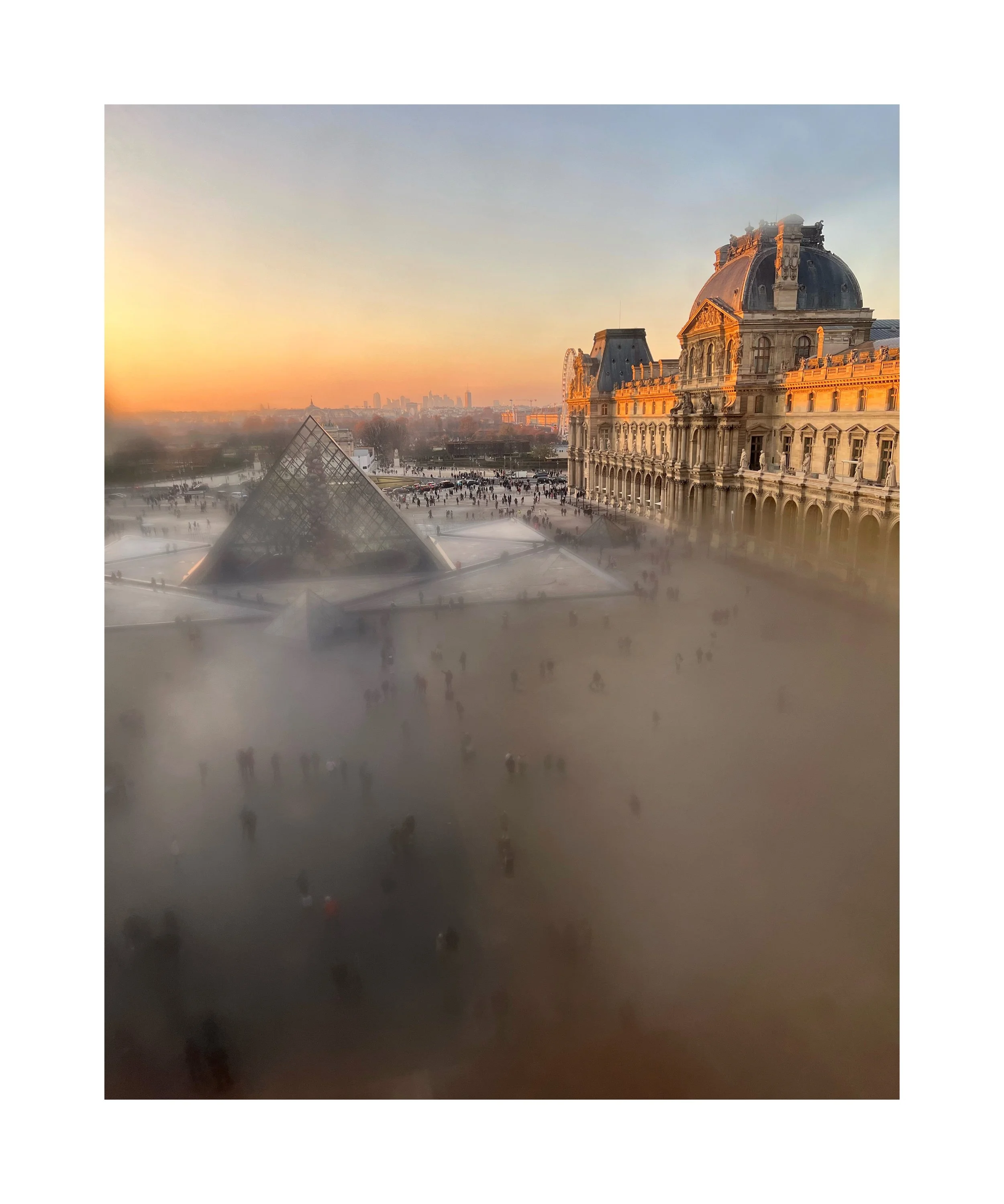 Vue du Louvre à Paris au coucher du soleil, avec le musée et la pyramide en verre, et des touristes autour.