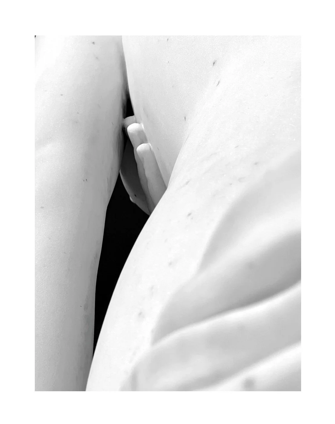 Prise de vue en noir et blanc d'une main entre deux draps ou tissus, avec seulement quelques doigts visibles.