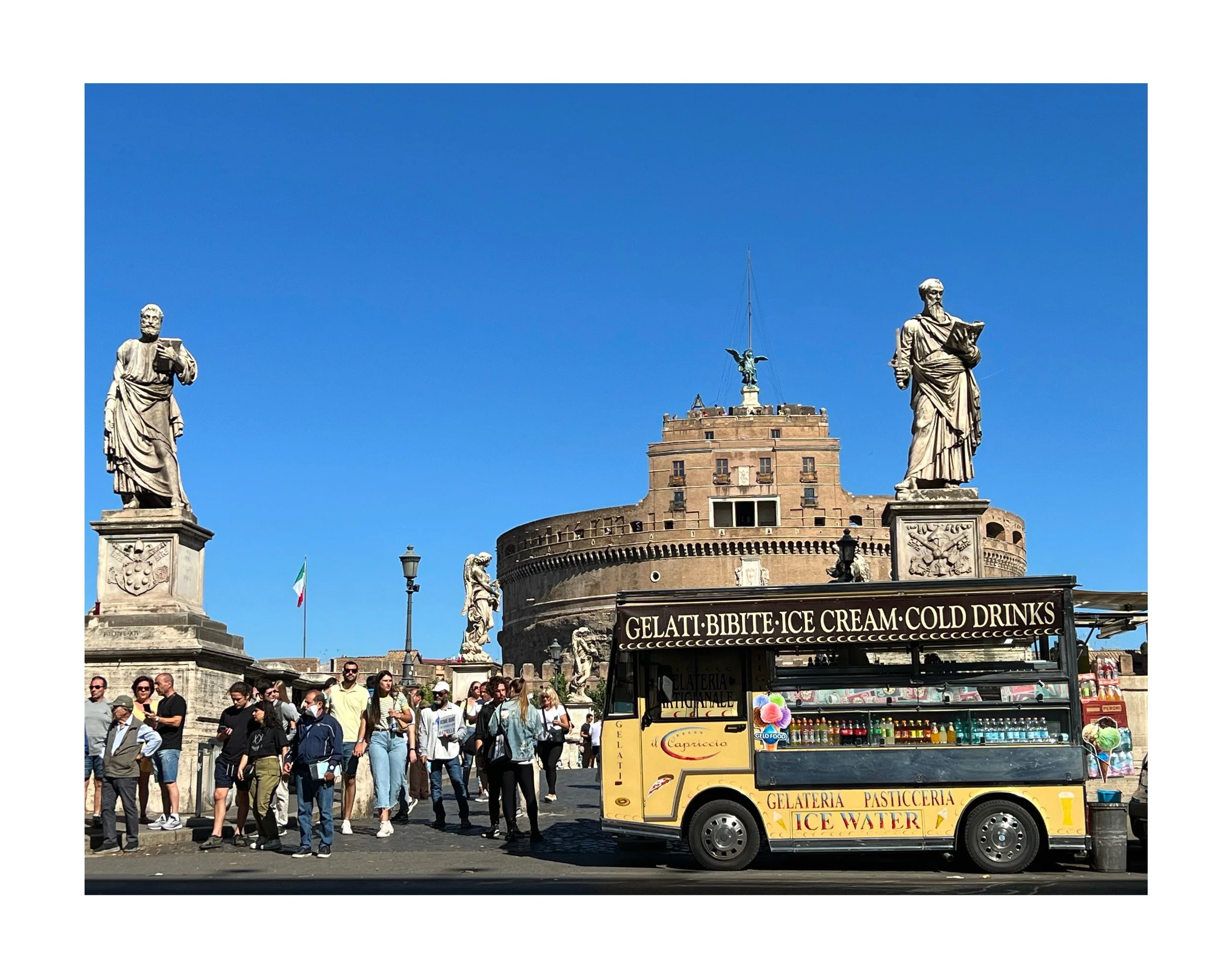 Une scène urbaine à Rome avec une foule de personnes devant un château historique, la Castel Sant'Angelo, sous un ciel bleu clair. Il y a une charrette de glace jaune en premier plan, avec un panneau indiquant des glaces, boissons glacées, et eau, ai