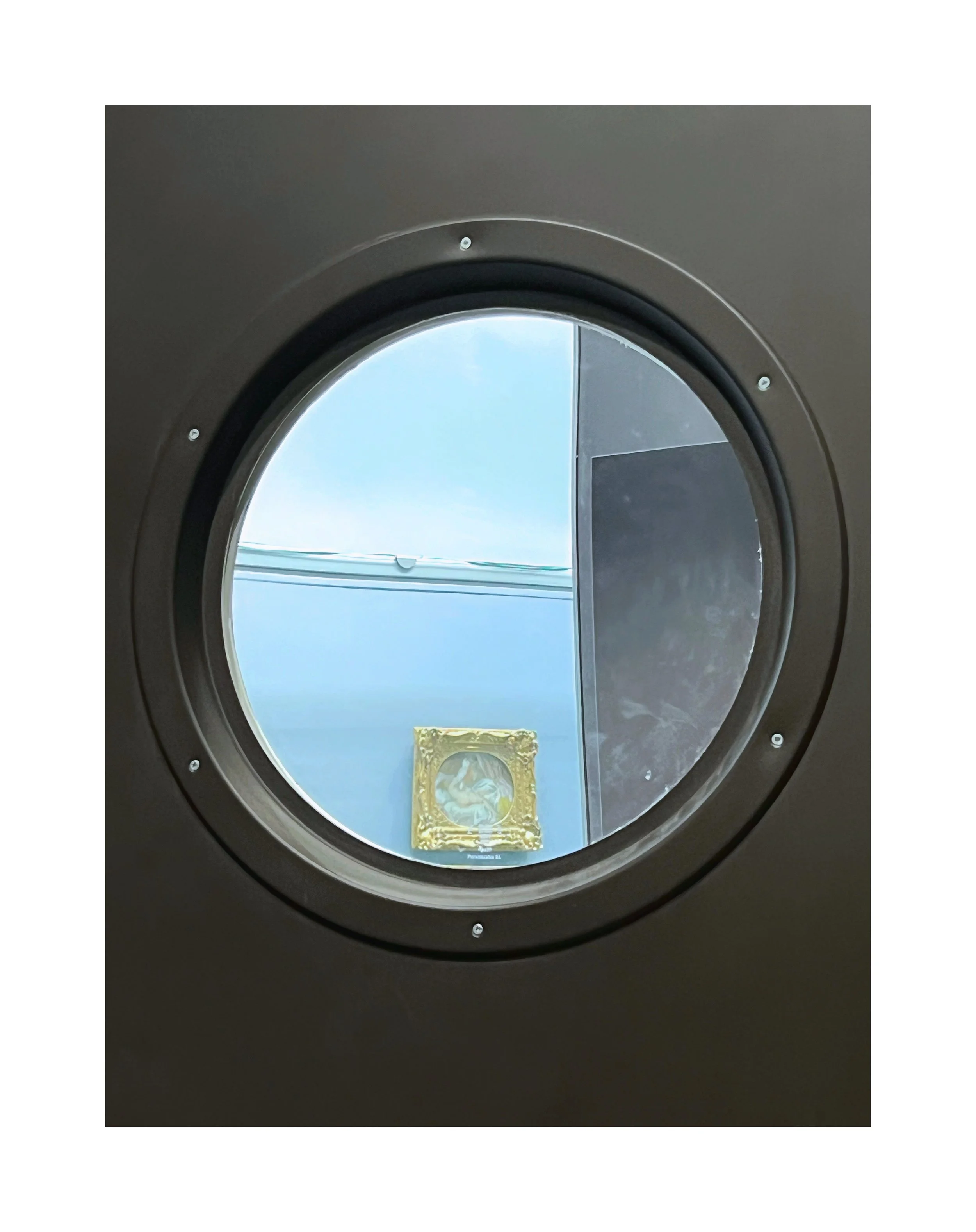 Vue à travers une fenêtre rondes d'une machine à laver, avec un cadre en métal noir et un fond clair.