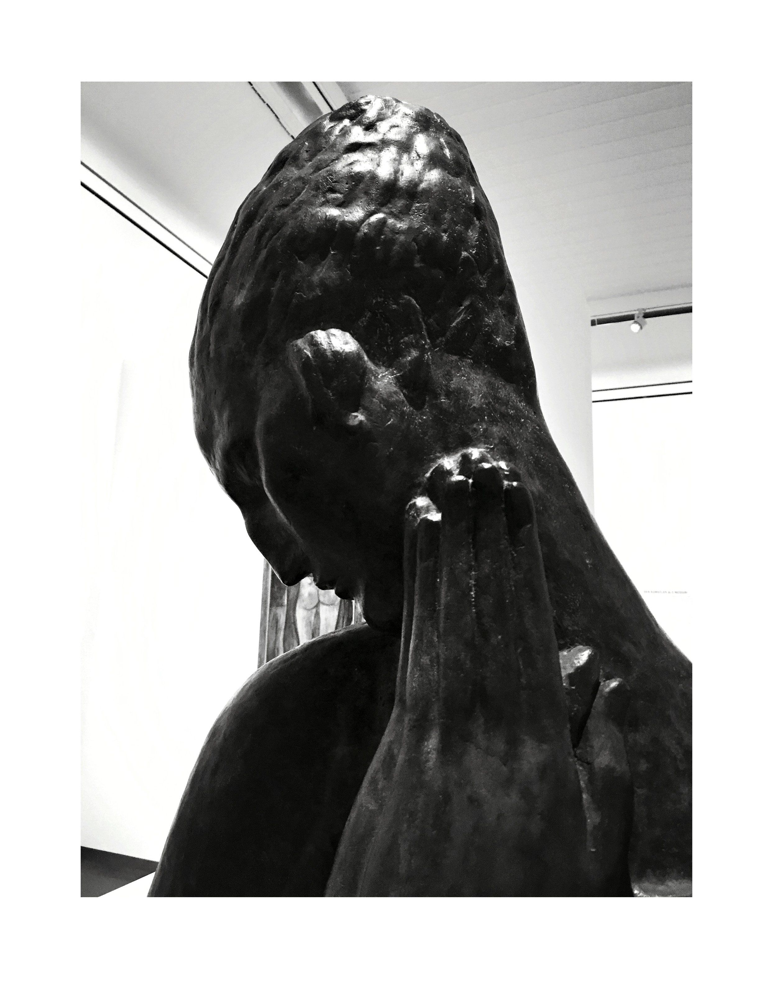 Sculpture en bronze d'une femme avec la tête inclinée et la main sur le visage, exposée dans un musée.