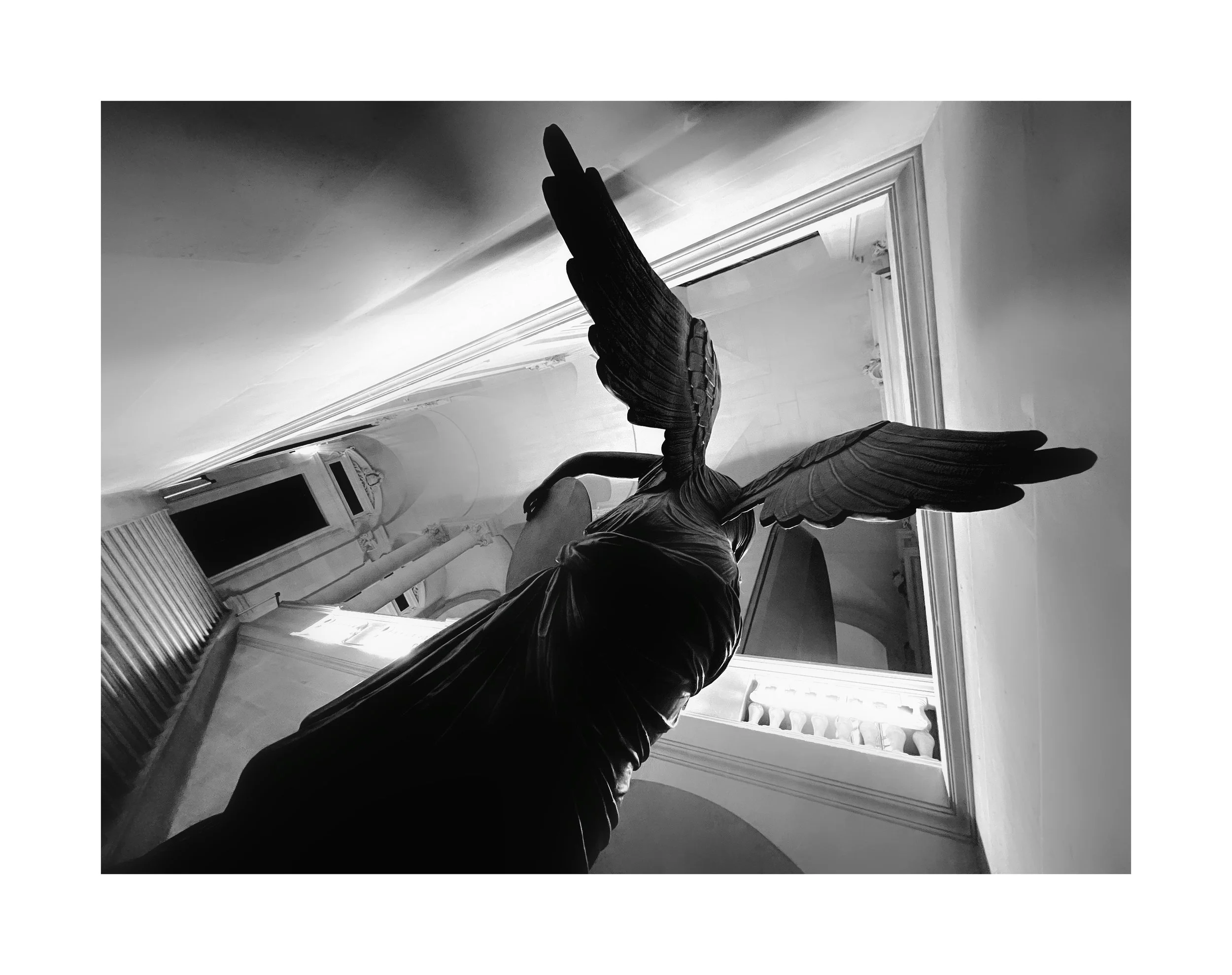 Une sculpture en forme d'ange avec de grandes ailes en bois, vue en gros plan, dans un intérieur lumineux.