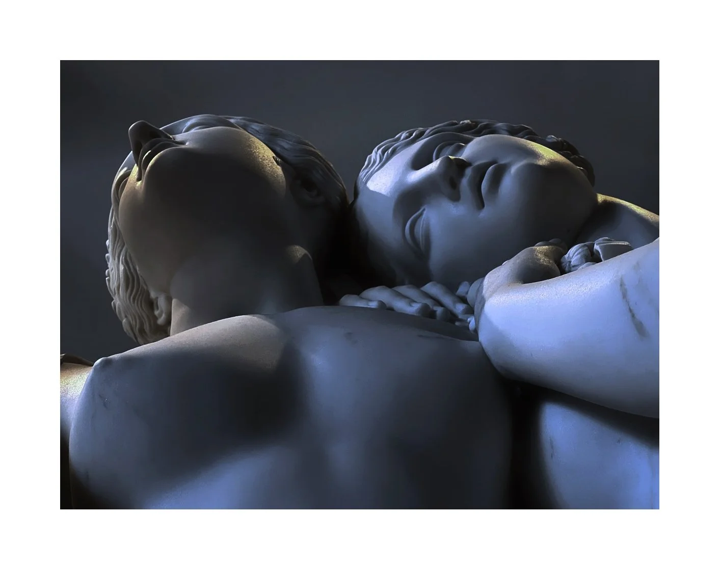 Statue de deux personnes allongées, une homme et une femme, dans un style classique, avec une expression de tendresse et d'intimité, éclairage doux mettant en valeur les détails de la sculpture.