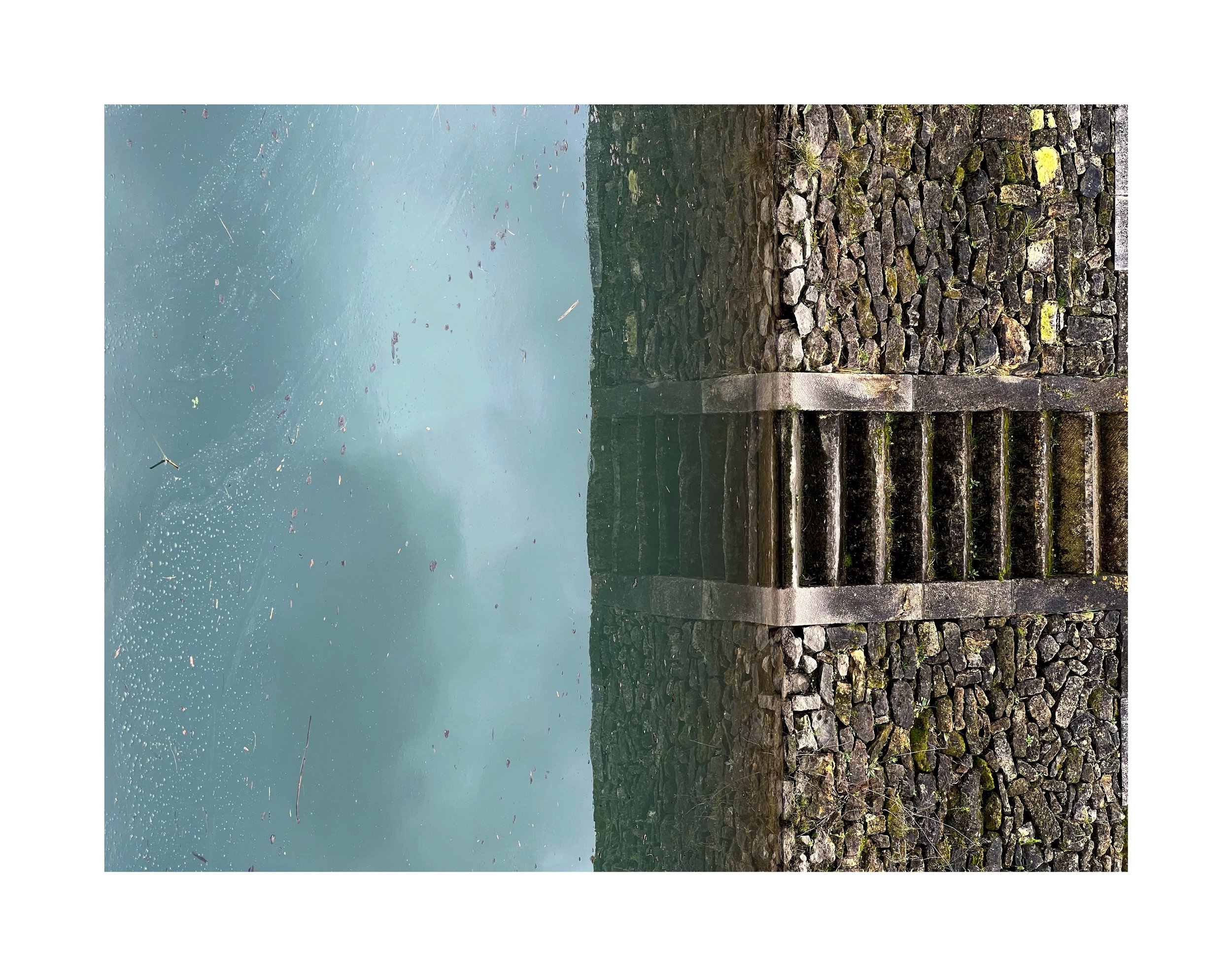 Escalier en pierre menant vers un plan d'eau avec de la fumée ou du brouillard, entouré de rochers et de végétation derrière.