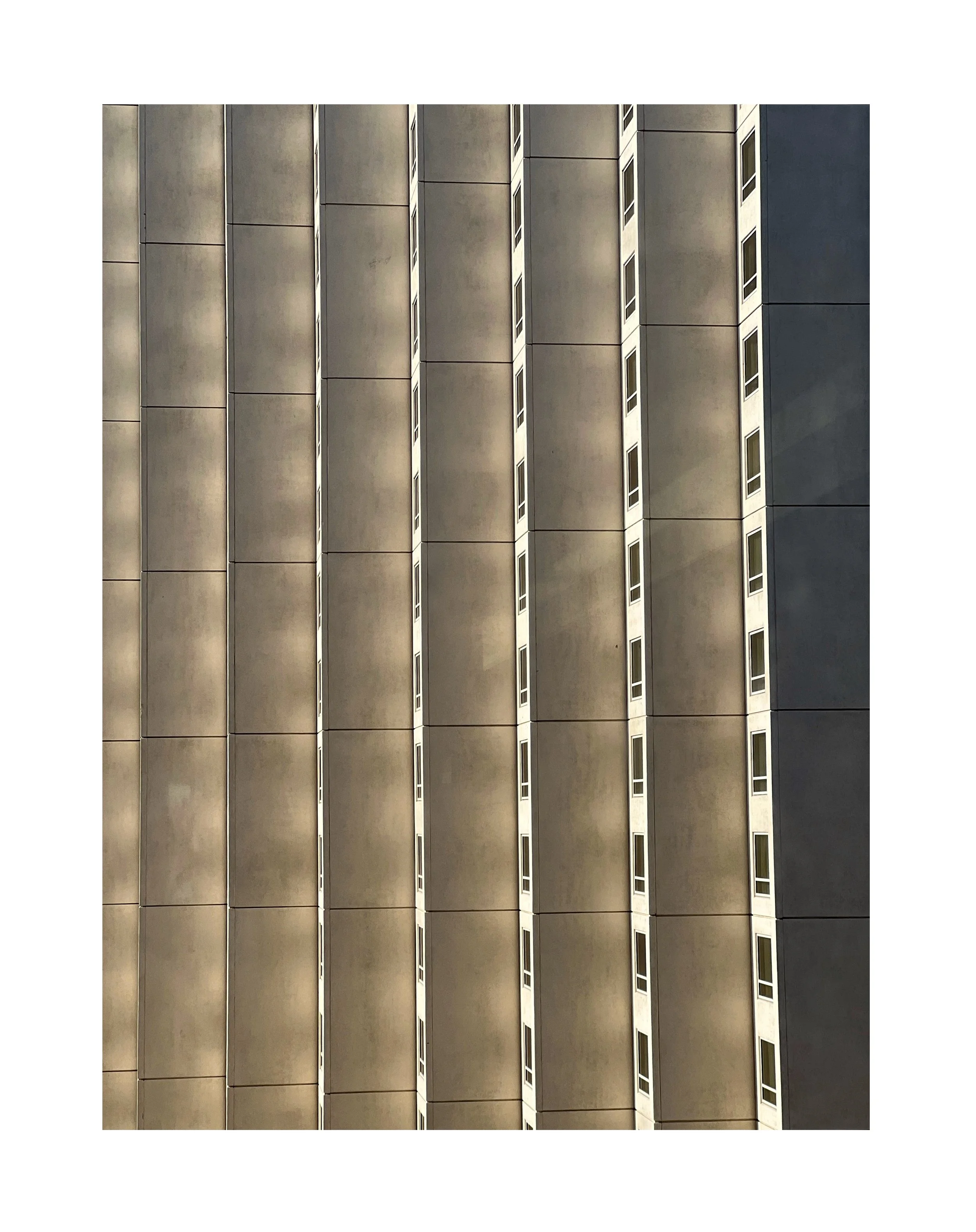 Façade d’un immeuble avec plusieurs fenêtres en rangées verticales, vue en contre plongée