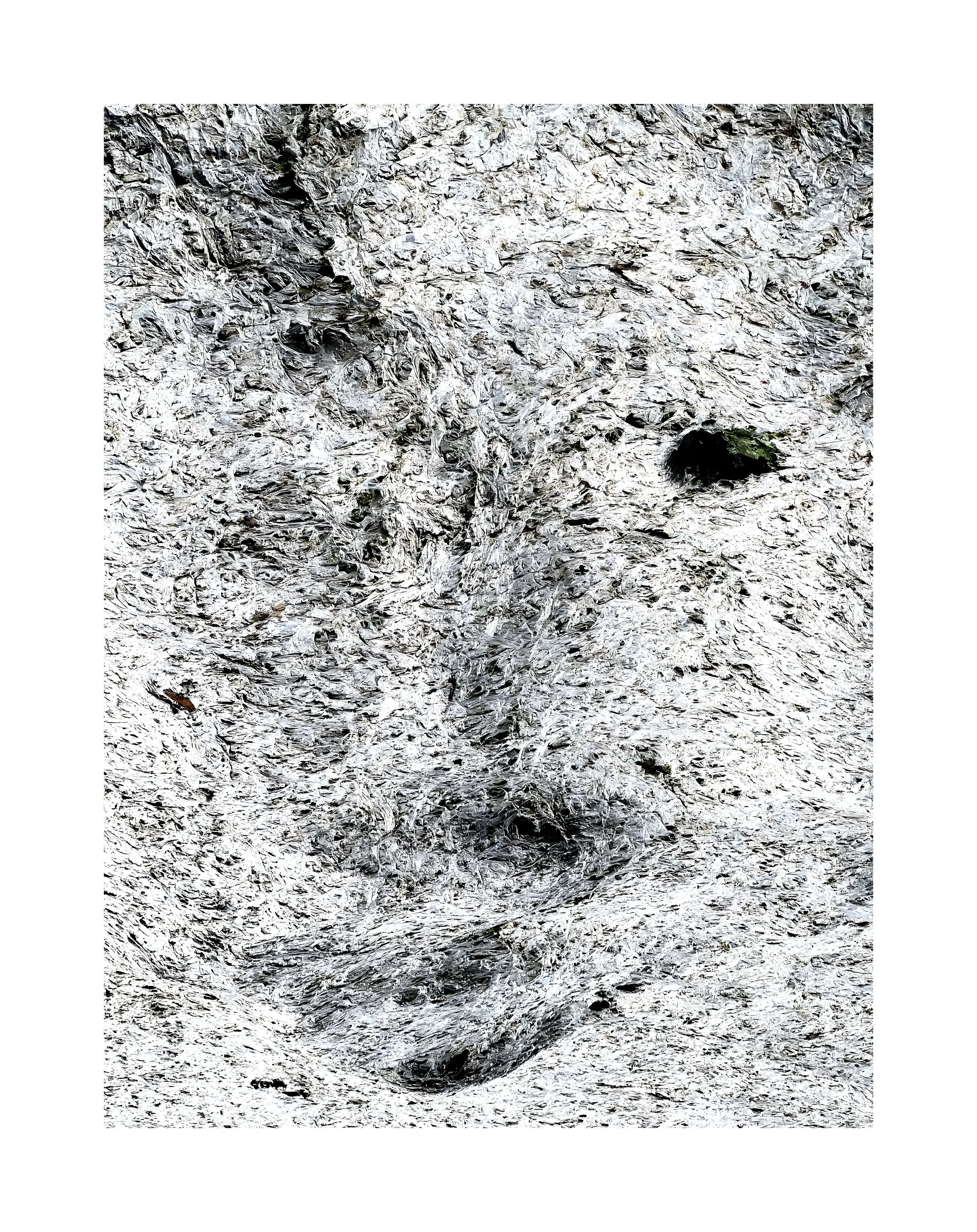 Surface rocheuse blanche avec quelques taches noires et vertes.