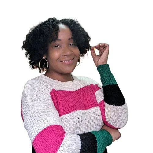 Young woman with curly black hair wearing a colorful striped sweater and hoop earrings, smiling and holding a lock of hair.