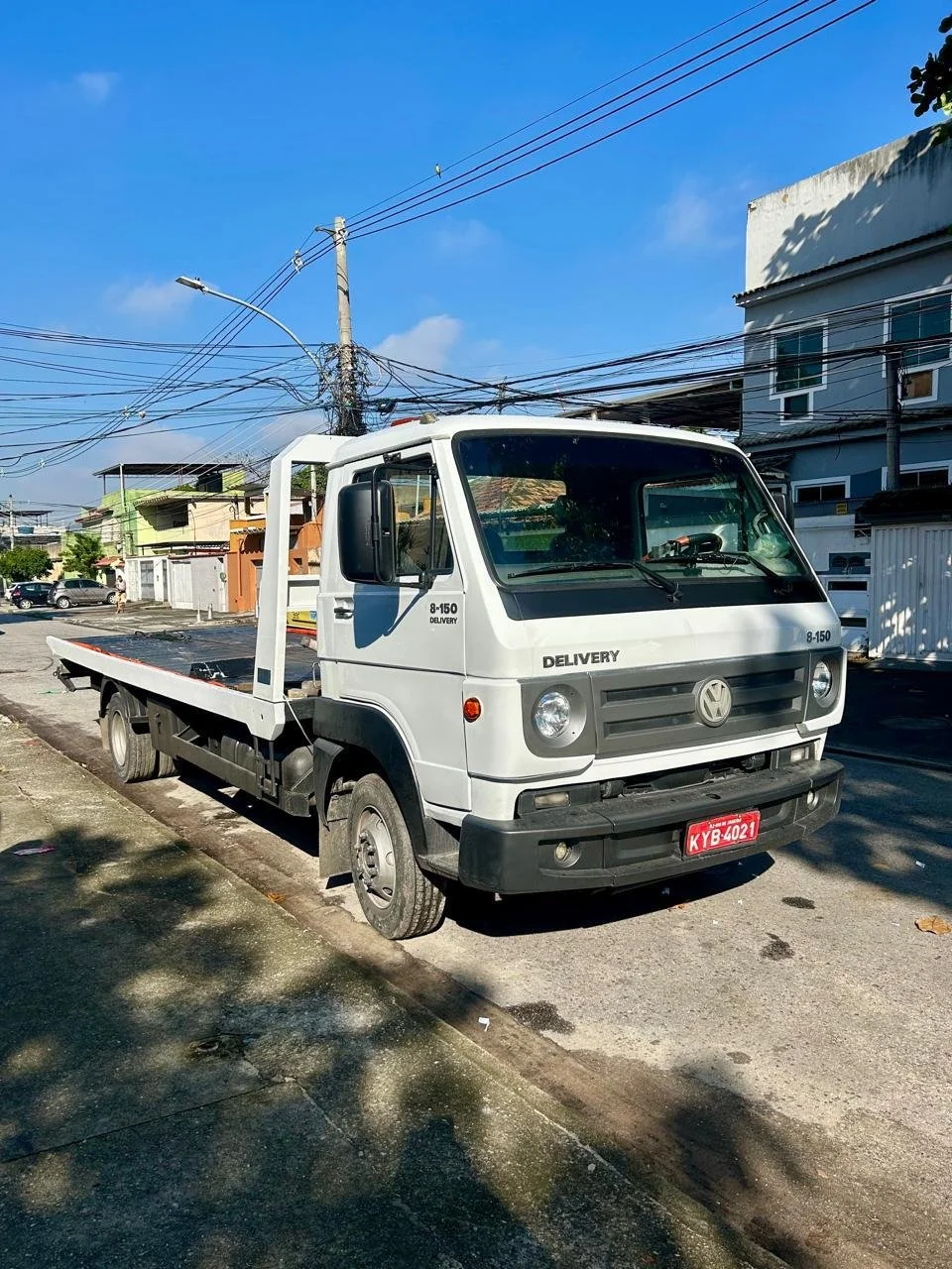 Caminhão de entrega Volkswagen branco estacionado na rua em dia ensolarado.