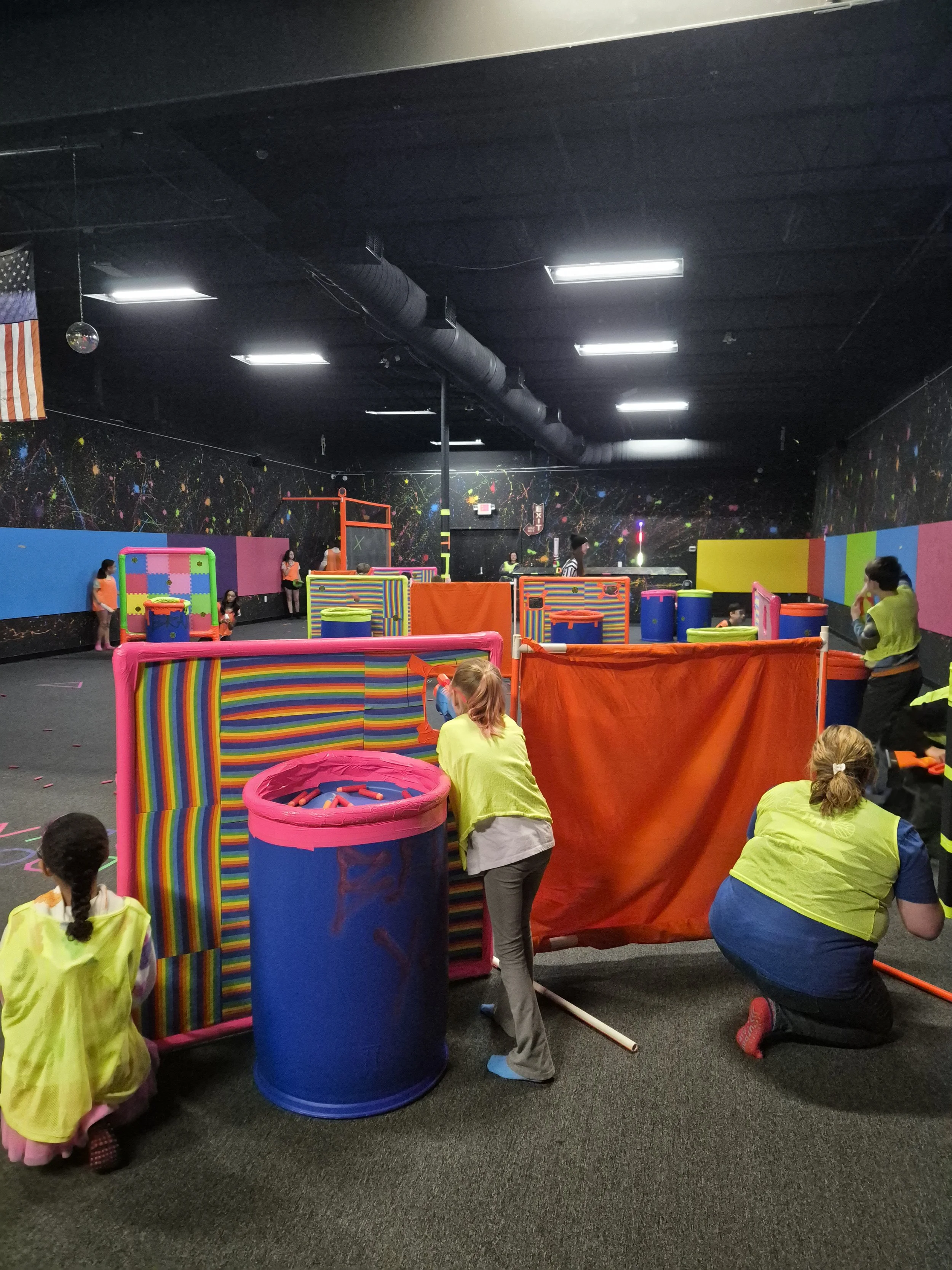 Kids playing laser tag in an indoor arcade with colorful walls and equipment.