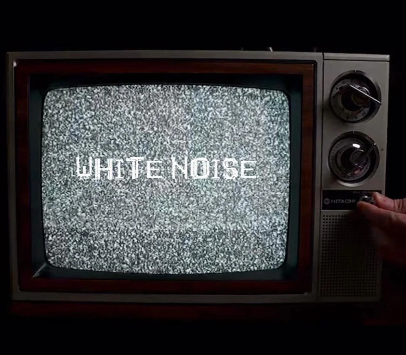 Vintage television displaying static with the words 'White Noise' in the center.