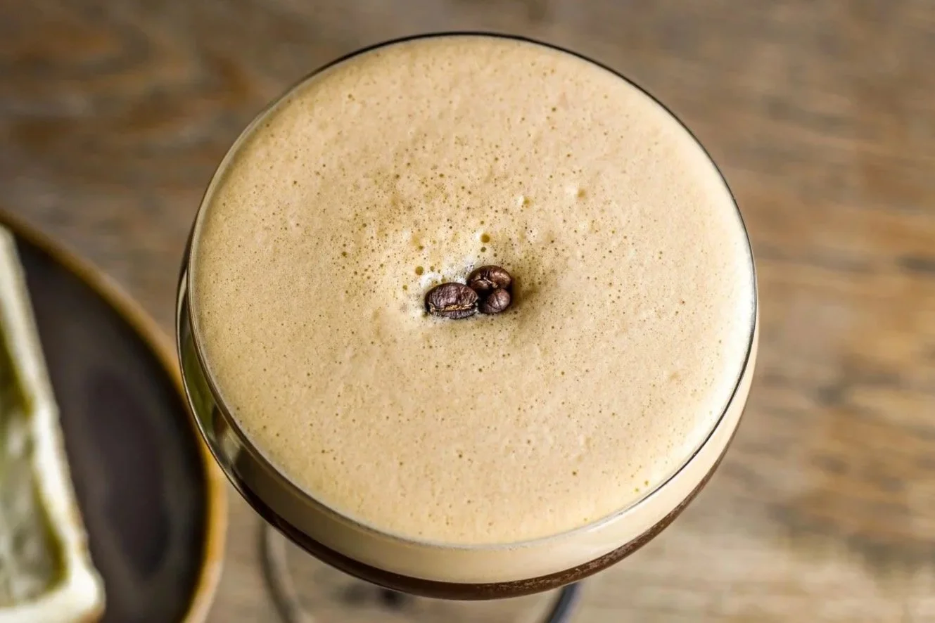 Close-up of a coffee cocktail garnished with coffee beans, on a wooden surface.