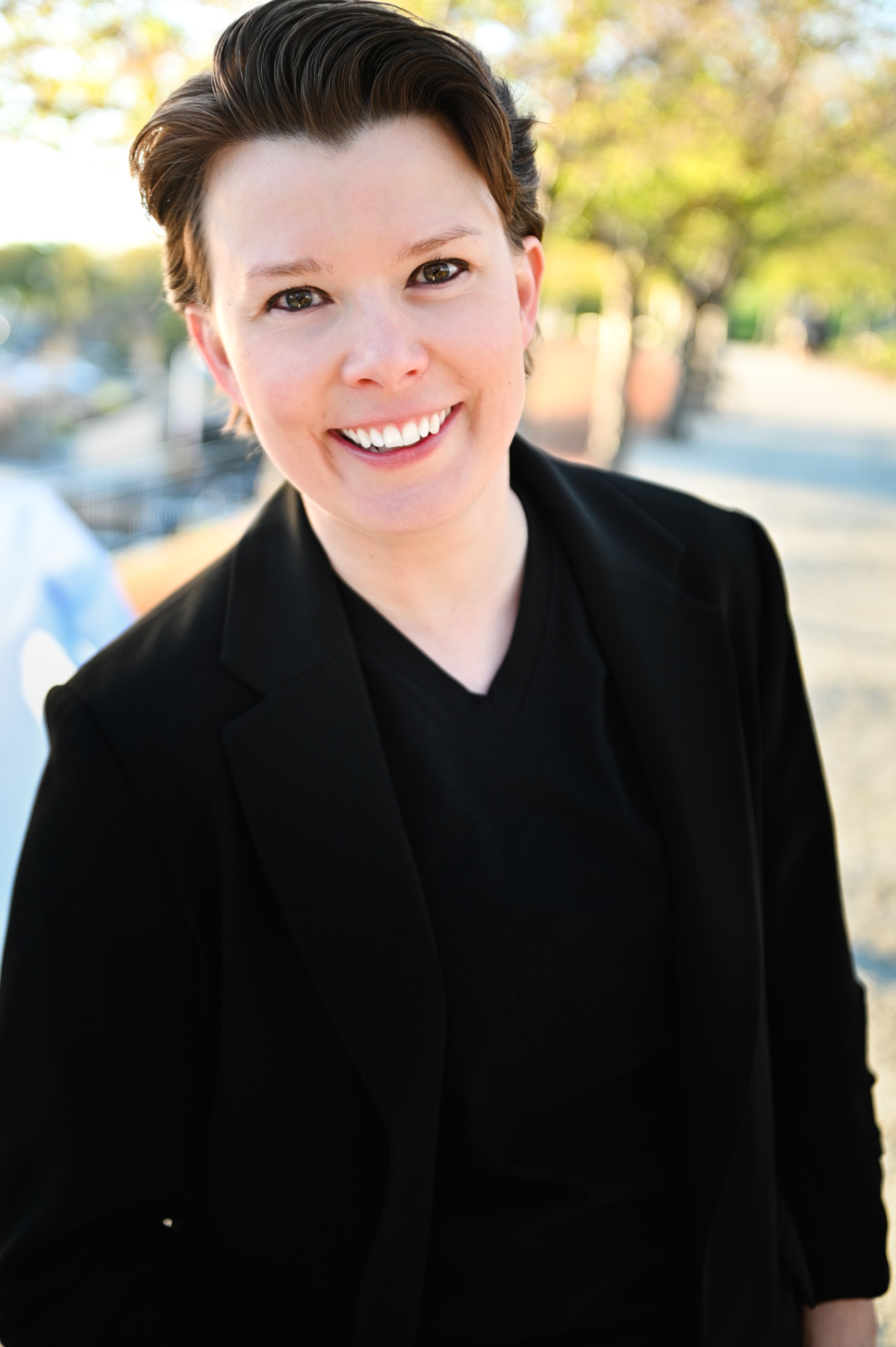 Q Porschatis, trauma therapist and founder of Salty Counseling in Salt Lake City, smiling outdoors.
