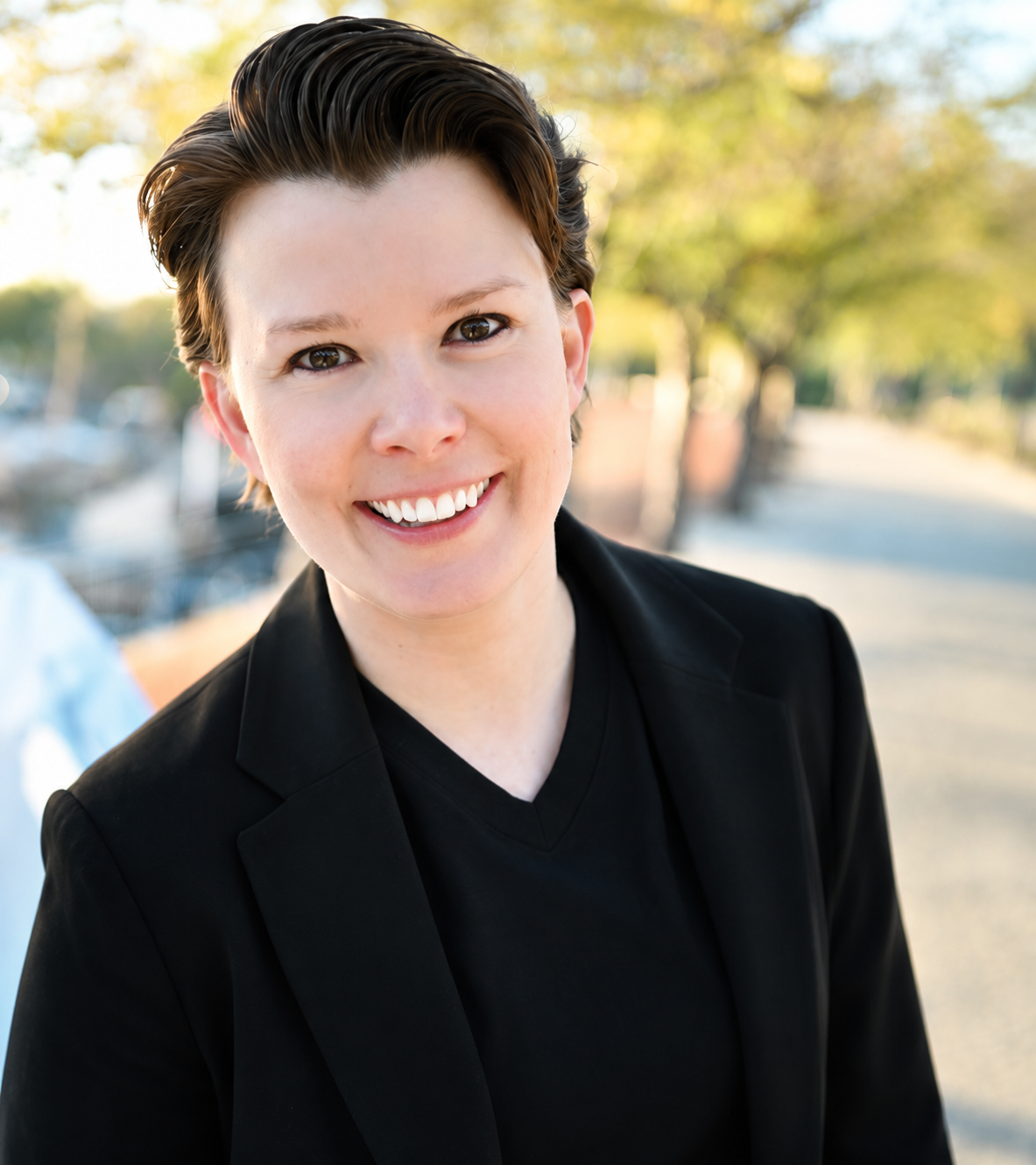 Q Porschatis, trauma therapist and founder of Salty Counseling in Salt Lake City, smiling outdoors.