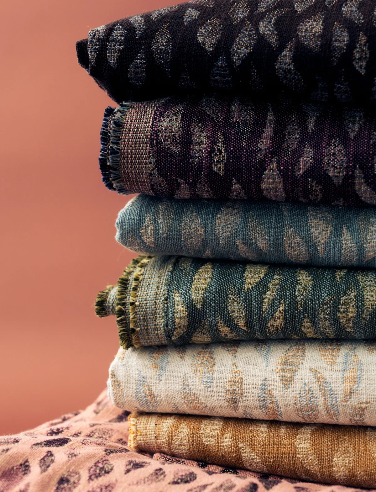 Close-up of folded Rebecca Atwood Petals woven fabric in black, plum, blue, green, ivory and ochre colorways
